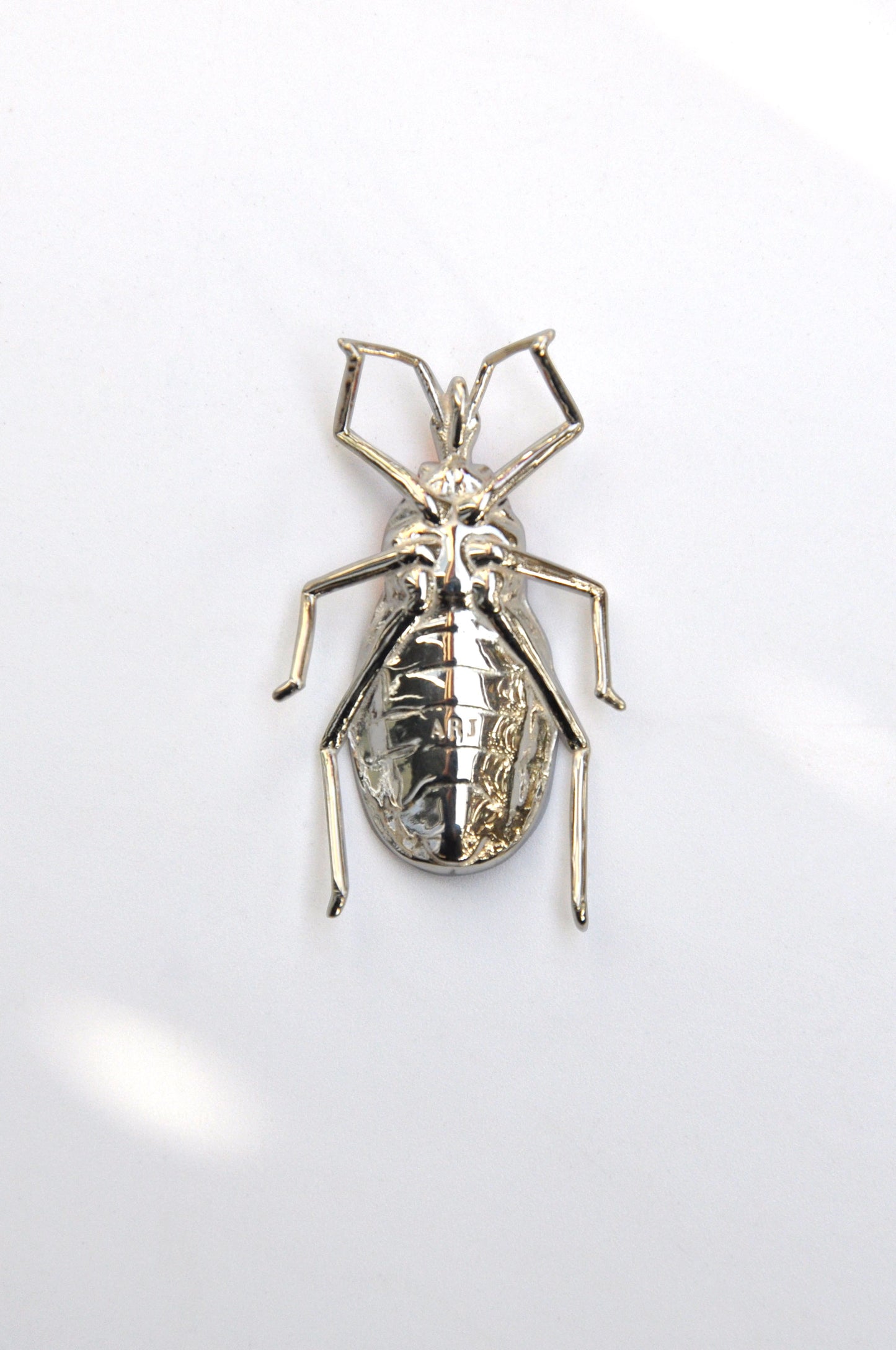 Back view of the sterling silver Assassin Bug pendant showing the ARJ maker’s mark and sculptural insect‑inspired metalwork.