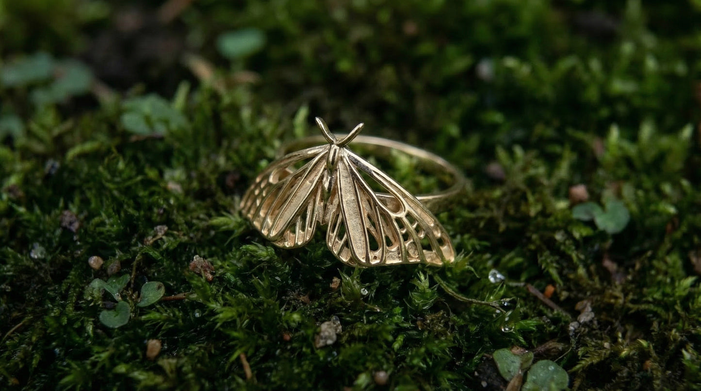 Gold butterfly-shaped ring on a green mossy surface