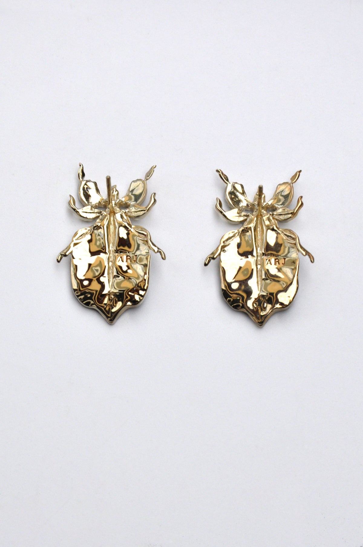 Pair of gold Phylliidae leaf‑inspired stud earrings with polished surfaces and sculptural detailing.