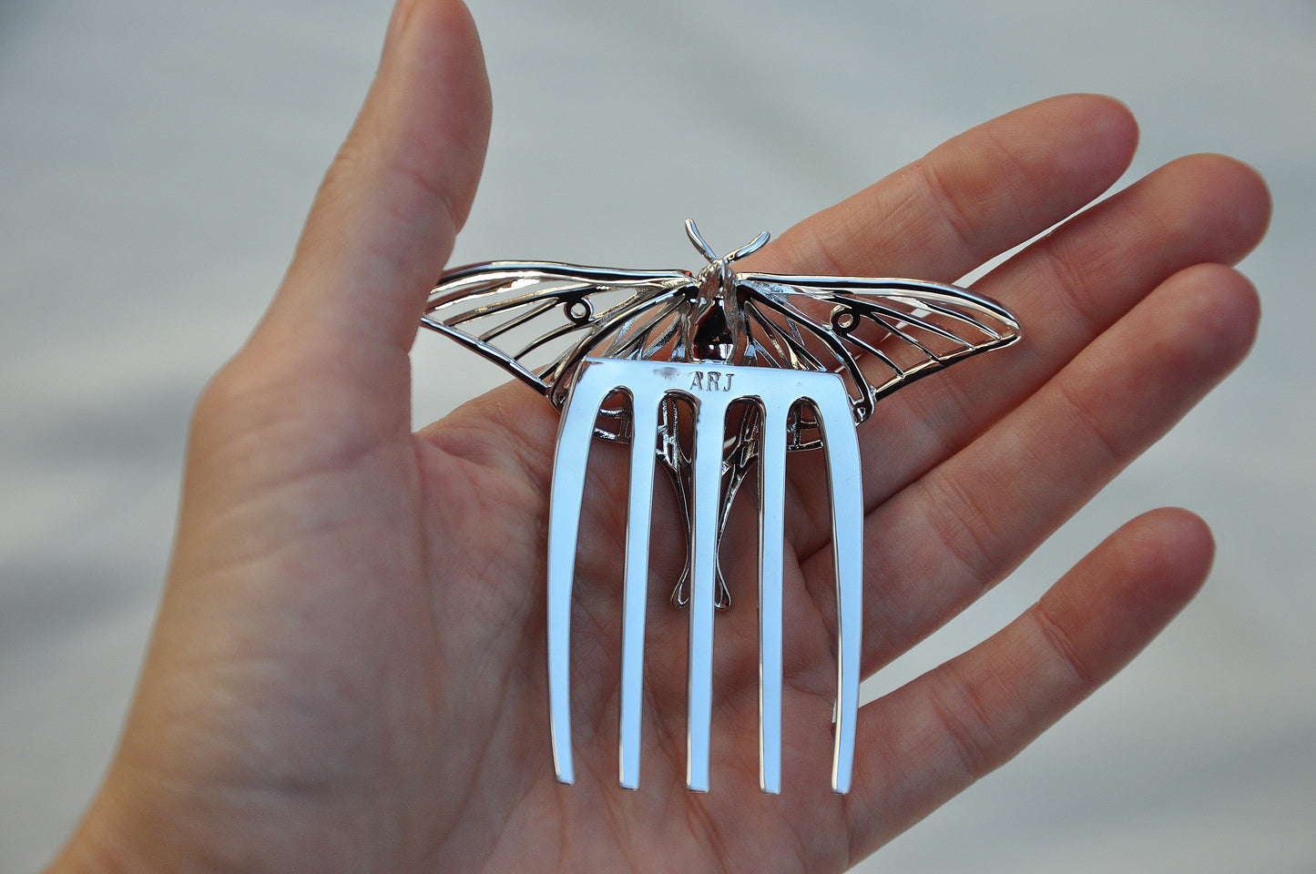 Back view of silver Luna Moth hair comb showing smooth polished finish, comb prongs, and handcrafted detailing in insect-inspired jewelry design.