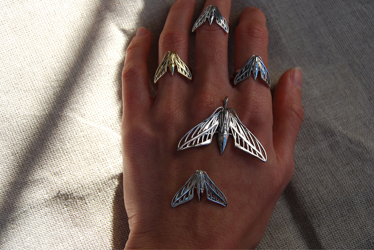 Final view of full sphinx moth ring collection in silver and gold worn on hand, highlighting handcrafted celestial design.