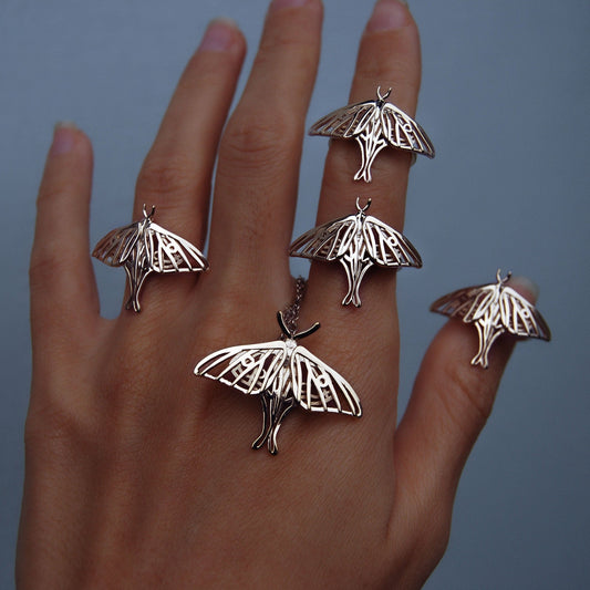 Hand wearing silver Luna moth jewelry with delicate wing details, nature-inspired accessory symbolizing transformation and elegance.