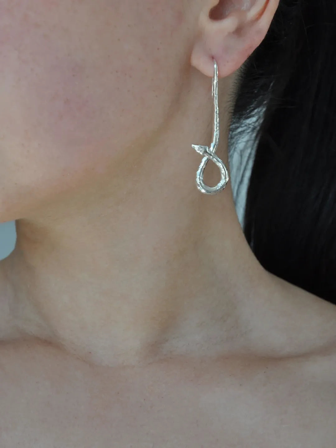 Asymmetrical botanical snake earring in polished sterling silver, worn on ear, designed in Italy.