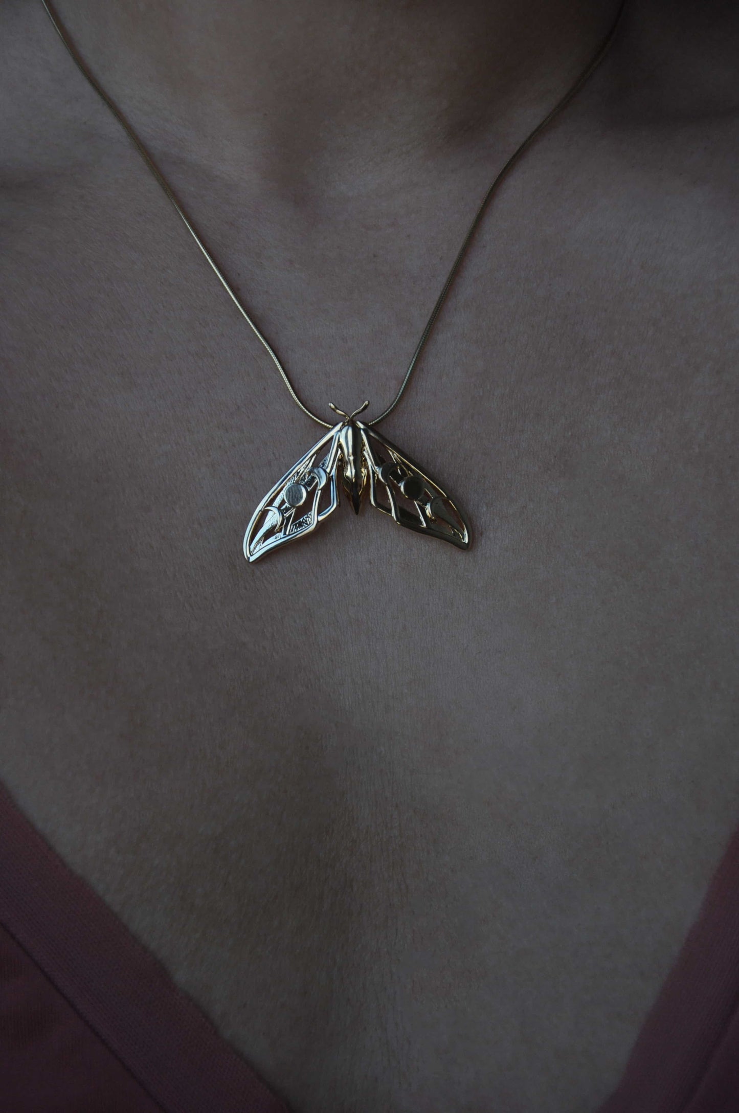Model wearing the gold plated Hawk Moth Pendant, illustrating its lightweight elegance and mystical symbolism.
