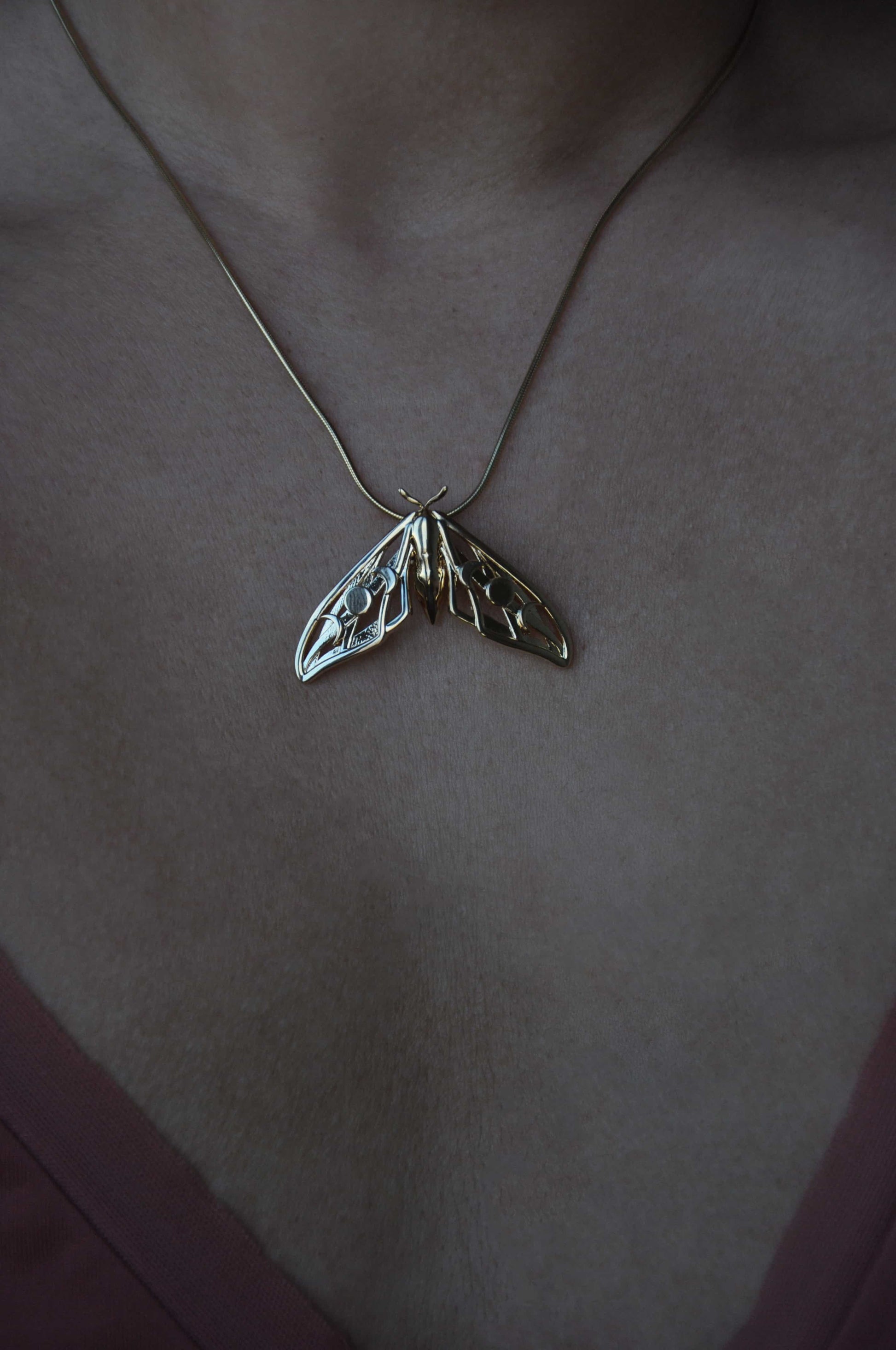 Model wearing the gold plated Hawk Moth Pendant, illustrating its lightweight elegance and mystical symbolism.