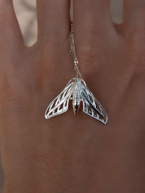 Close-up of a silver handcrafted sphinx moth pendant