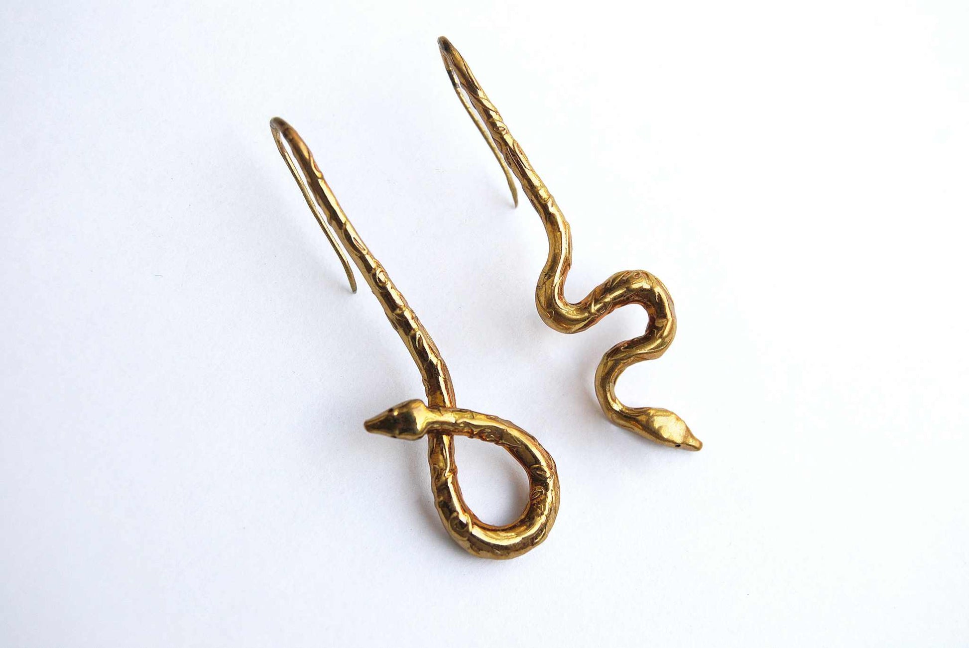 Asymmetrical botanical snake earrings in polished gold finish, designed in Italy with fine engraving.