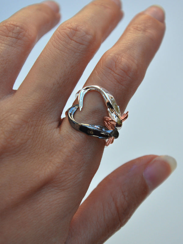 Front view of handcrafted Axolotl Stacking Ring Set forming a heart shape with tails — sterling silver and black rhodium axolotls with 14k rose gold gills.
