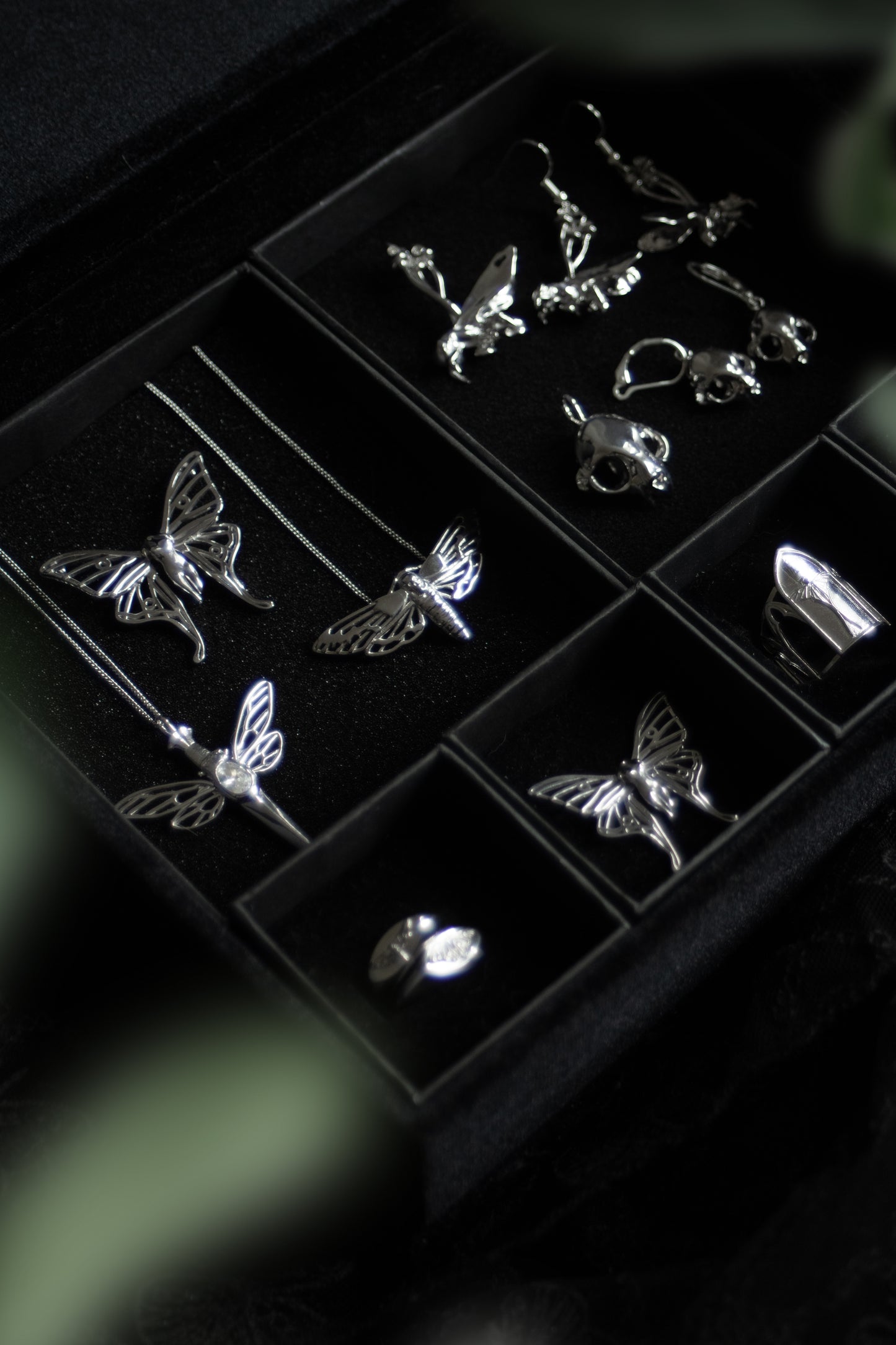 Death’s-head Hawk Moth pendant displayed on black velvet alongside other gothic jewelry pieces, emphasizing the dark aesthetic collection.