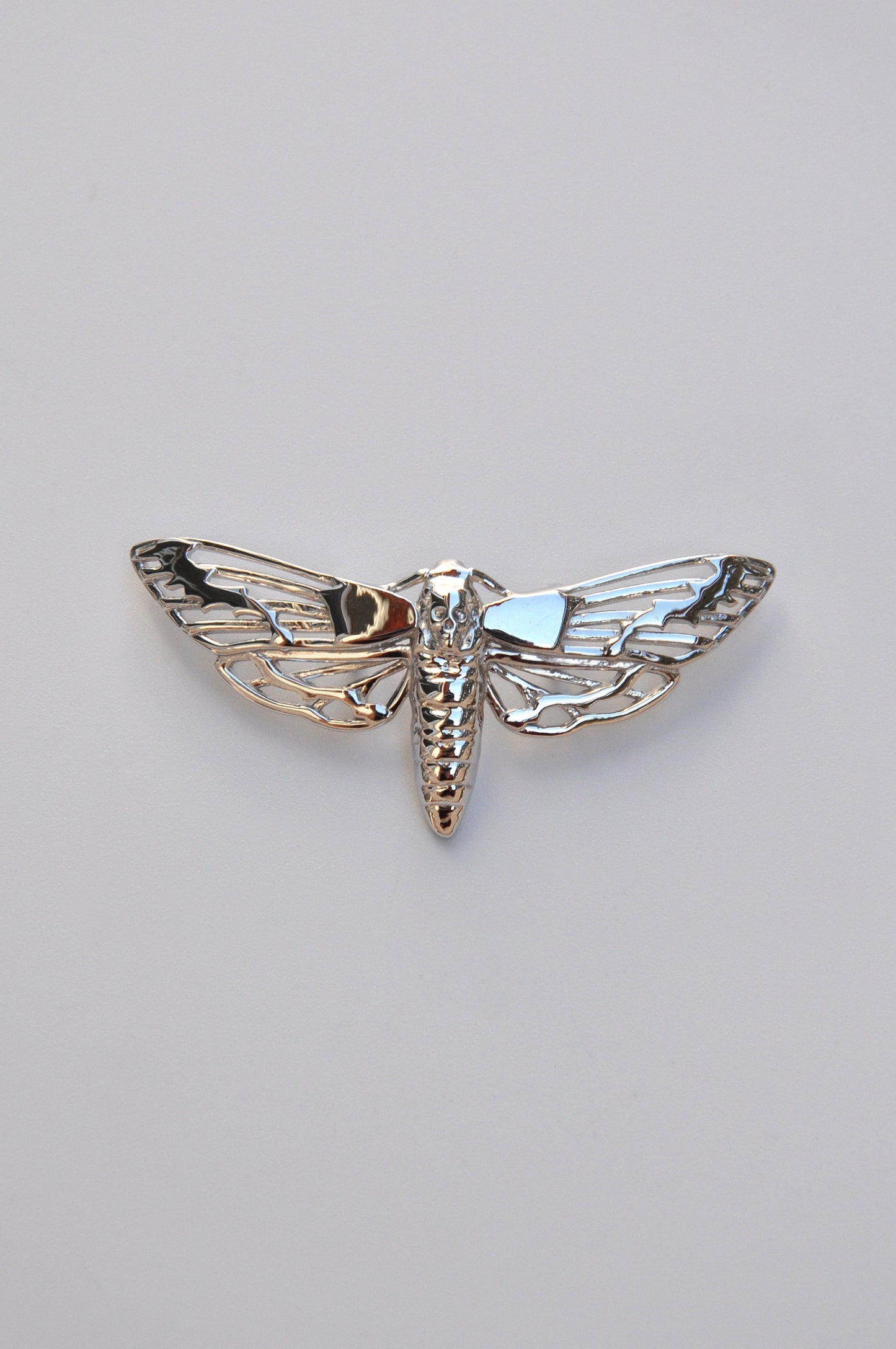 Front view of the Death’s-head Hawk Moth pendant in sterling silver on a white background, showing intricate skull and wing details.