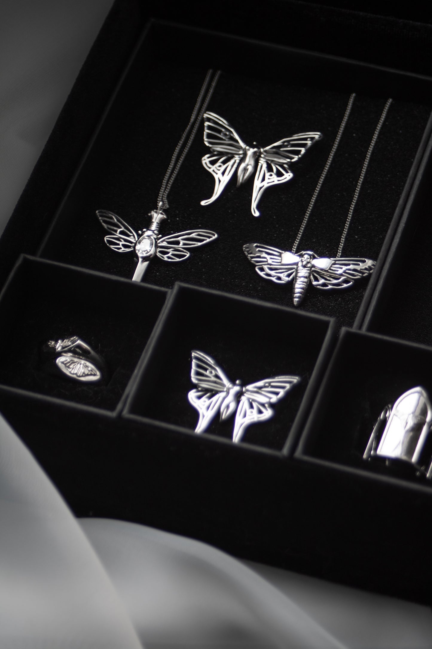 Close-up of the Death’s-head Hawk Moth pendant paired with matching gothic jewelry on black velvet display.