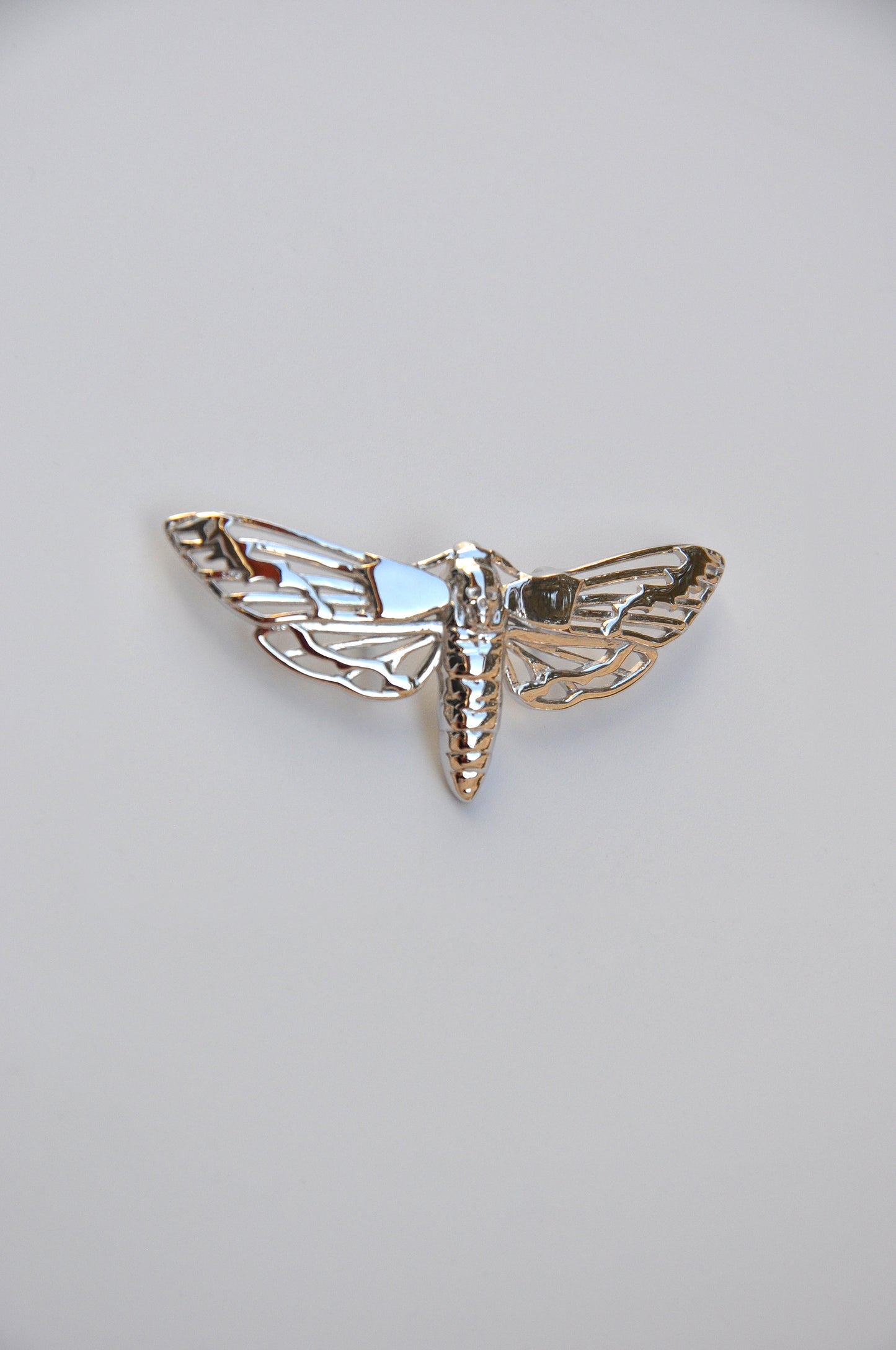 Side view of the silver Death’s-head Hawk Moth pendant on a white background, highlighting the clasp and finish.