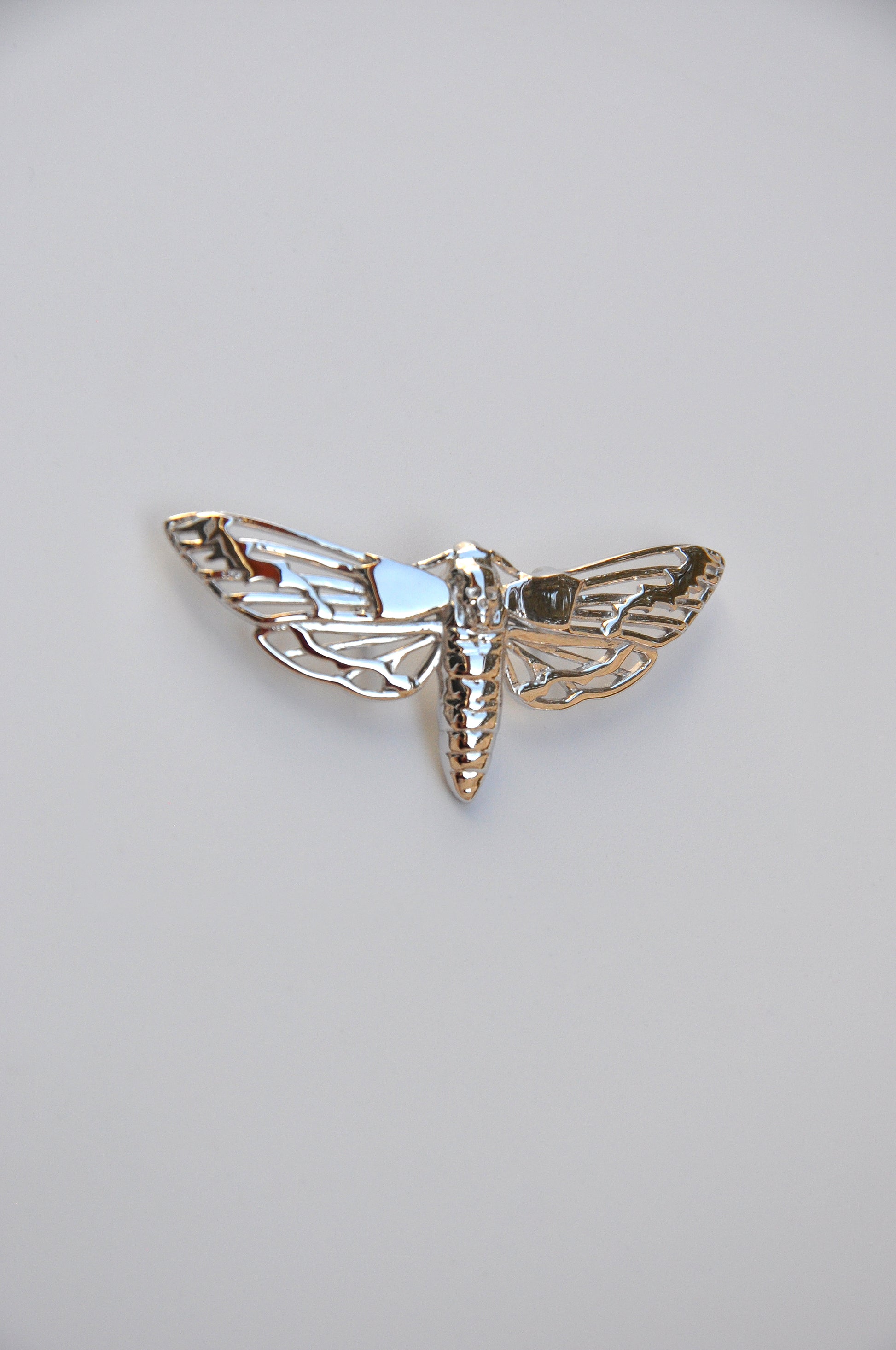 Side view of the silver Death’s-head Hawk Moth pendant on a white background, highlighting the clasp and finish.