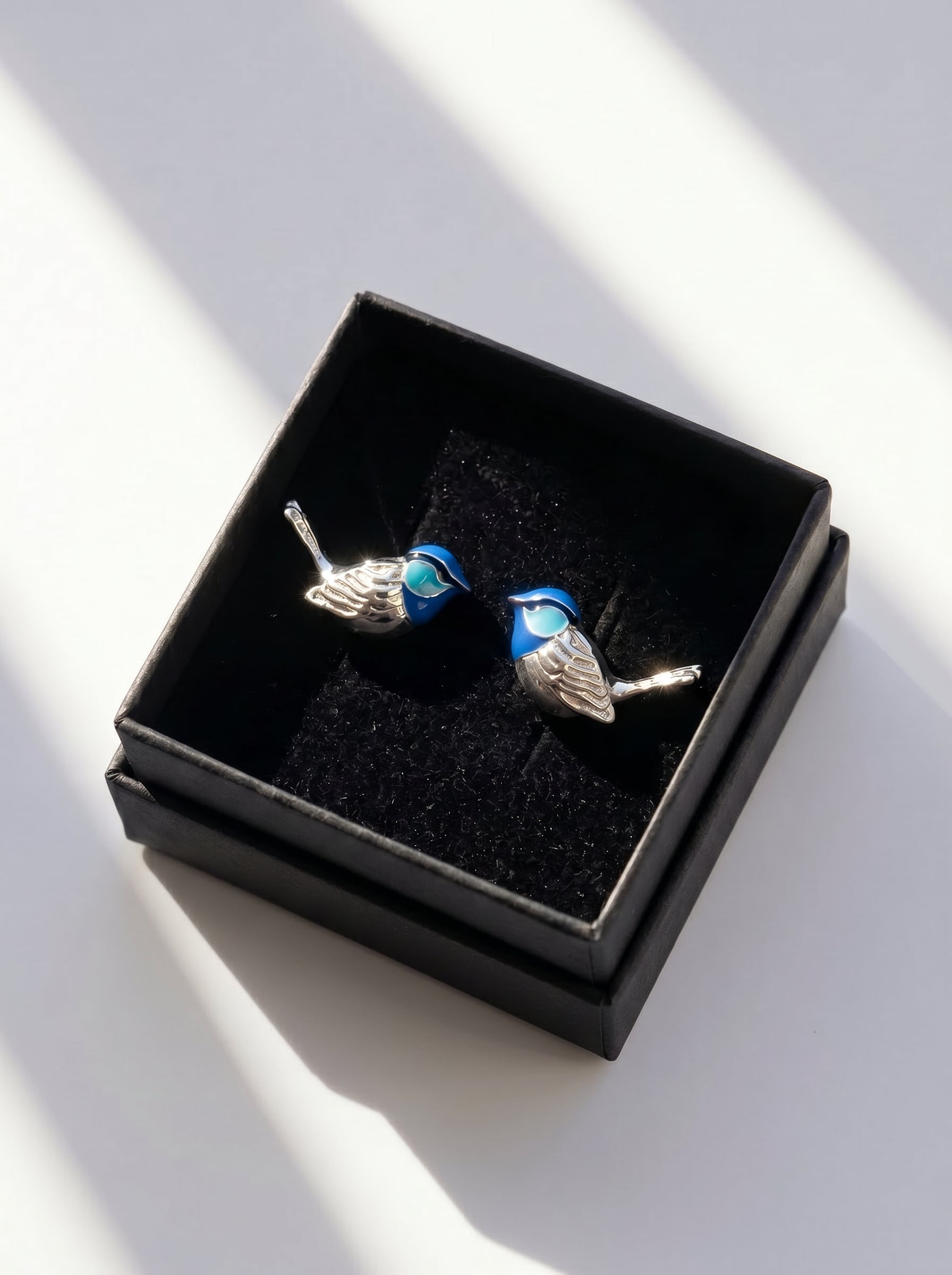 Fairy Wren stud earrings displayed in black jewelry box, emphasizing polished silver and hand‑applied enamel artistry.
