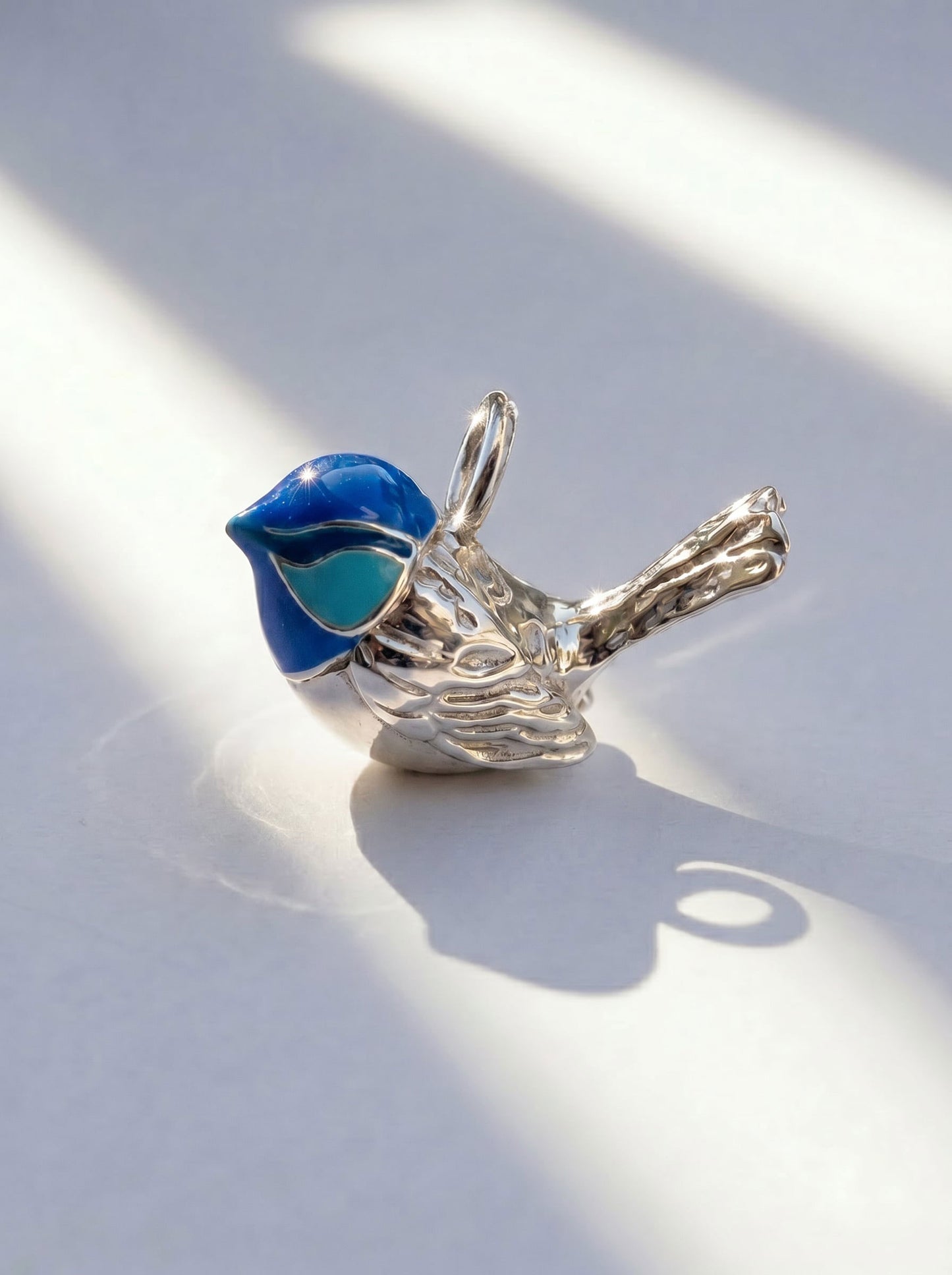 Angled view of Fairy Wren pendant in sterling silver, capturing fine tail engraving and deep blue enamel contrast.