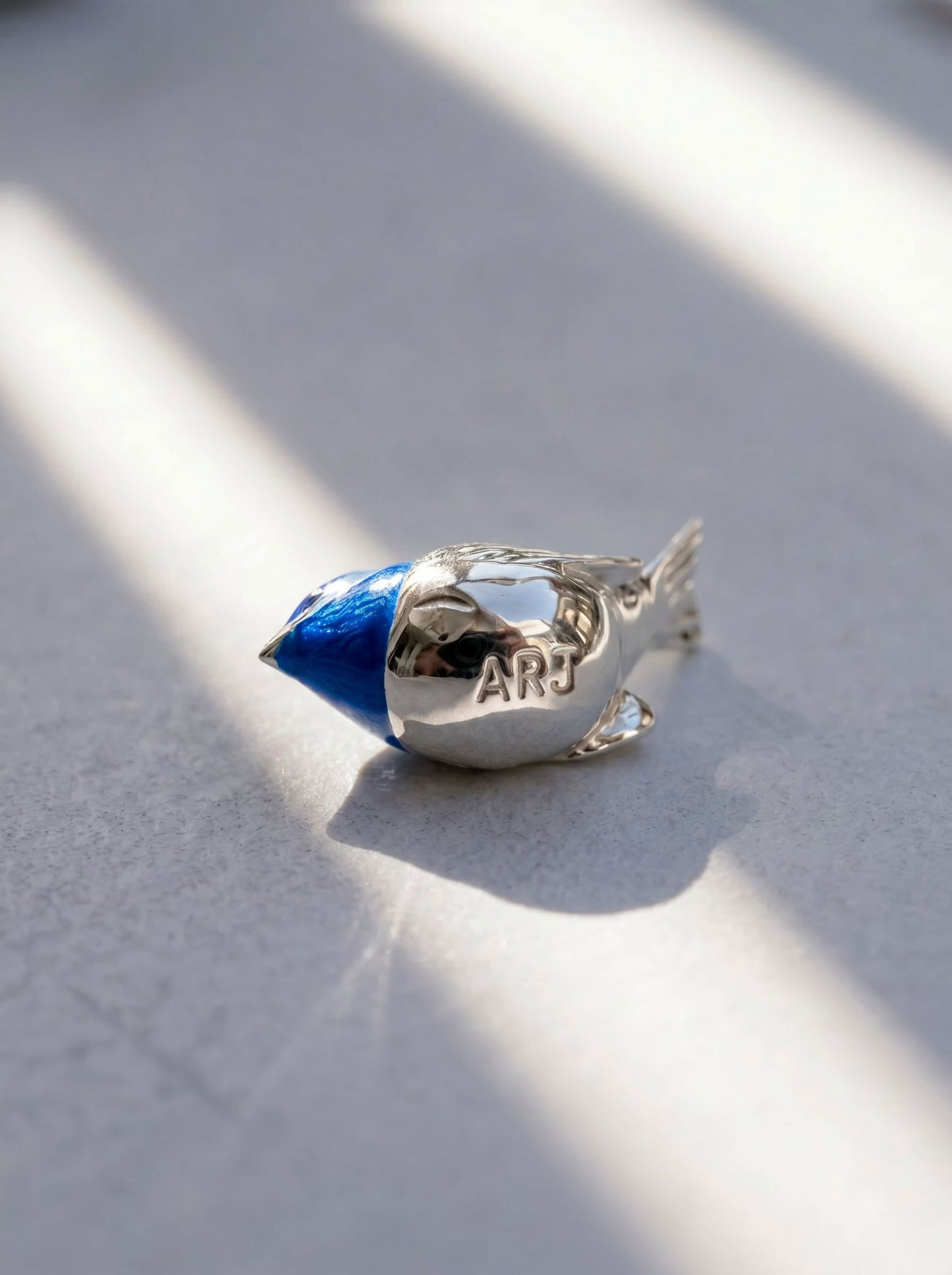 Side profile of Fairy Wren pendant, emphasizing polished silver texture and layered enamel artistry.