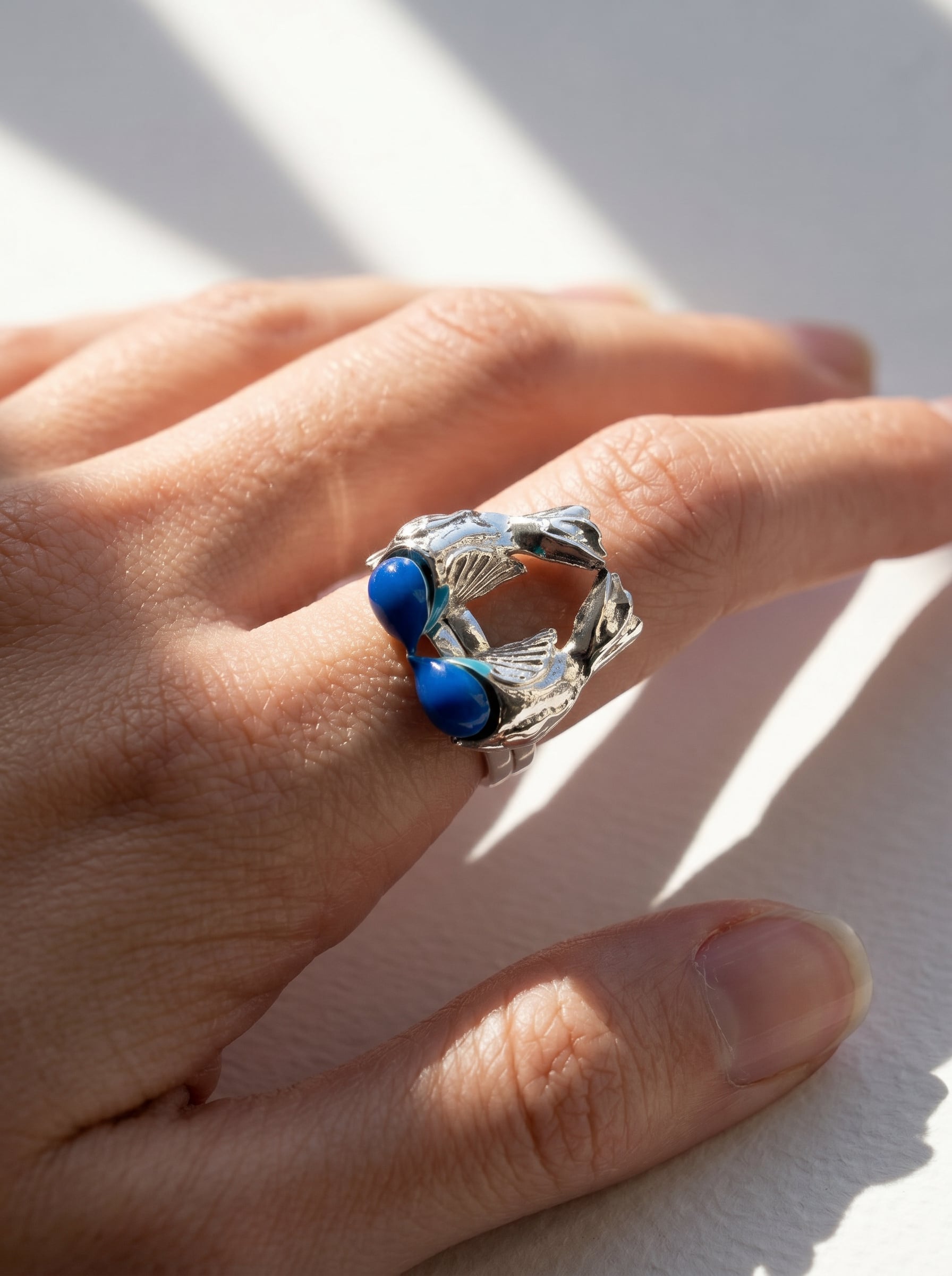 Fairy Wren stacking rings photographed on hand in natural light, revealing polished silver texture and electric turquoise enamel.