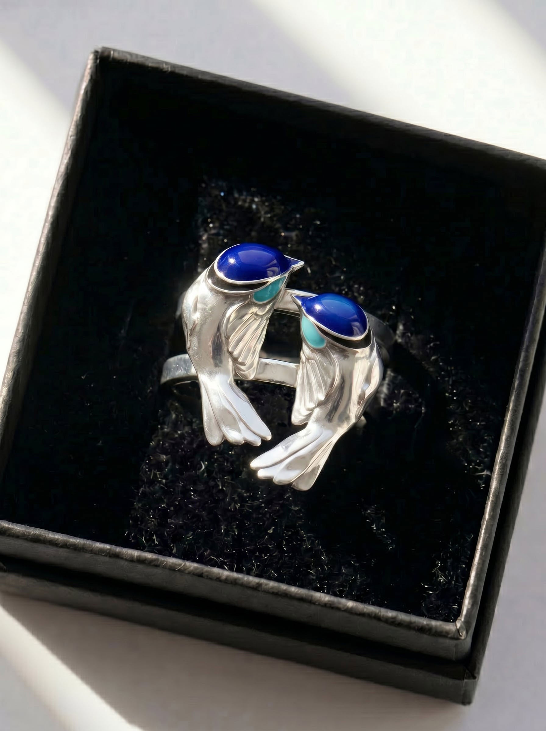 Fairy Wren stacking rings displayed in black jewelry box, showing polished silver and vivid blue enamel craftsmanship.