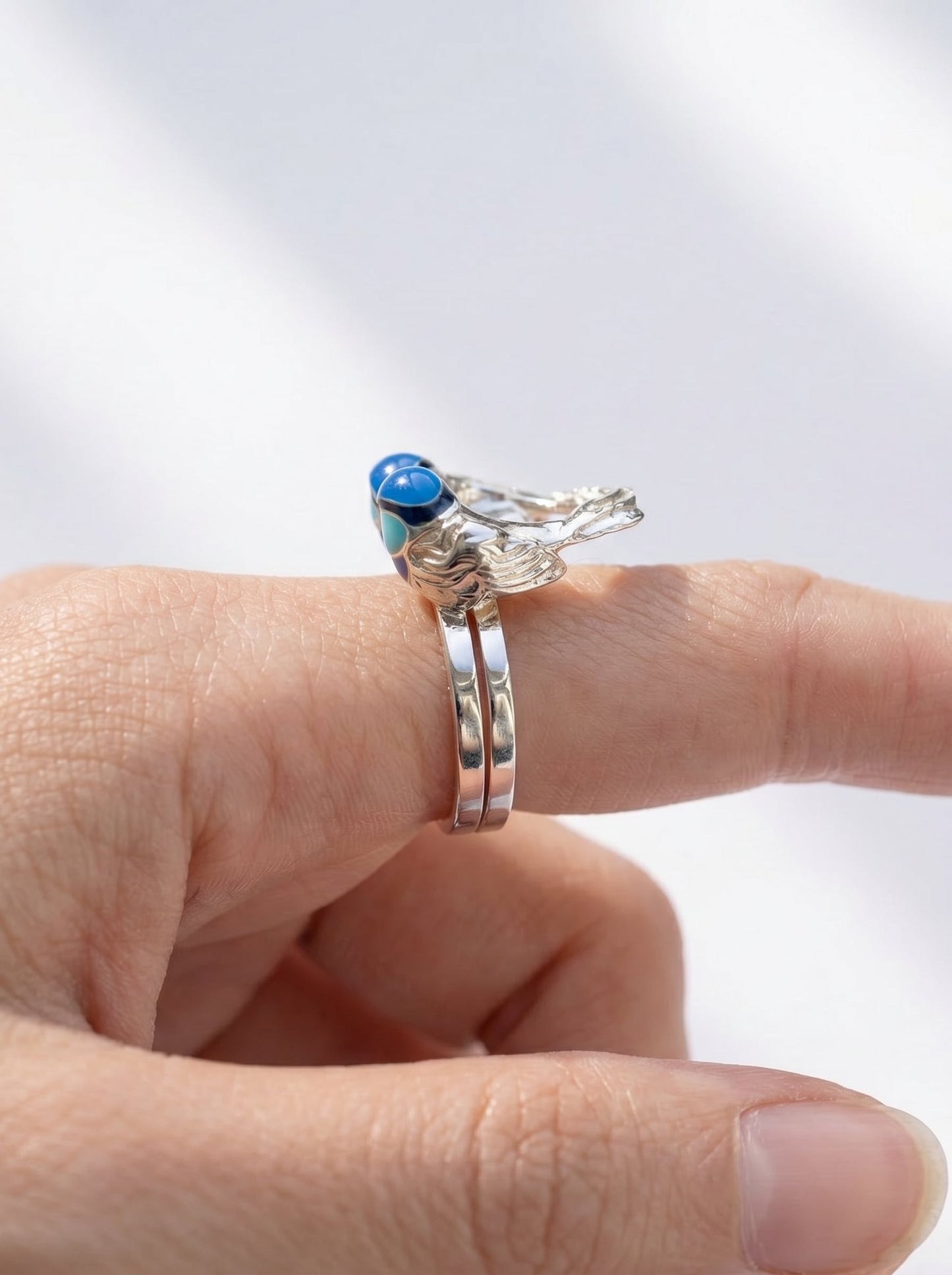 Side profile of Fairy Wren stacking rings worn together, showing alignment of sculptural birds and ring bands.