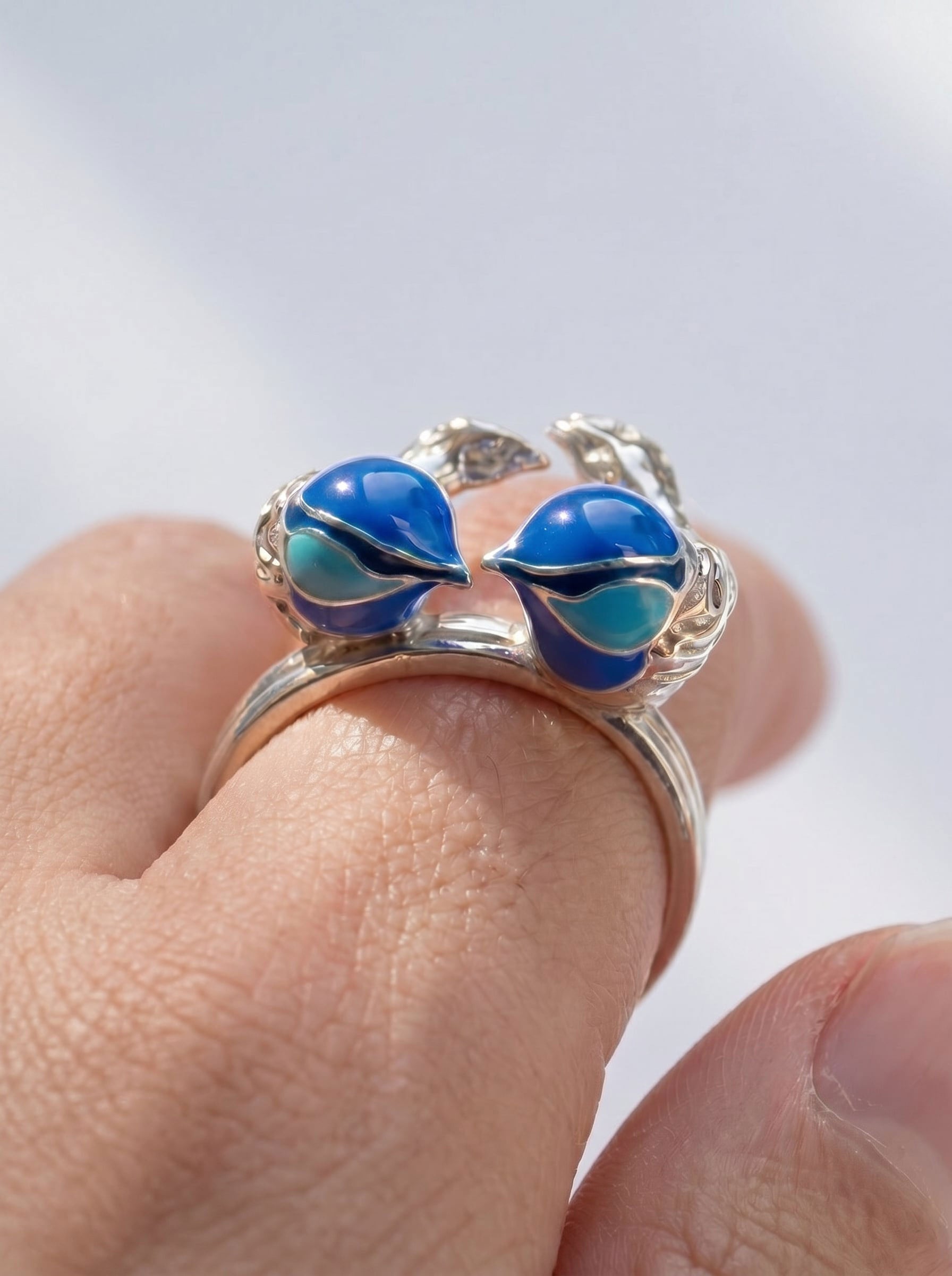 Close‑up of Fairy Wren stacking rings in sterling silver with hand‑applied blue enamel, showing the two birds facing each other in a heart‑like form.