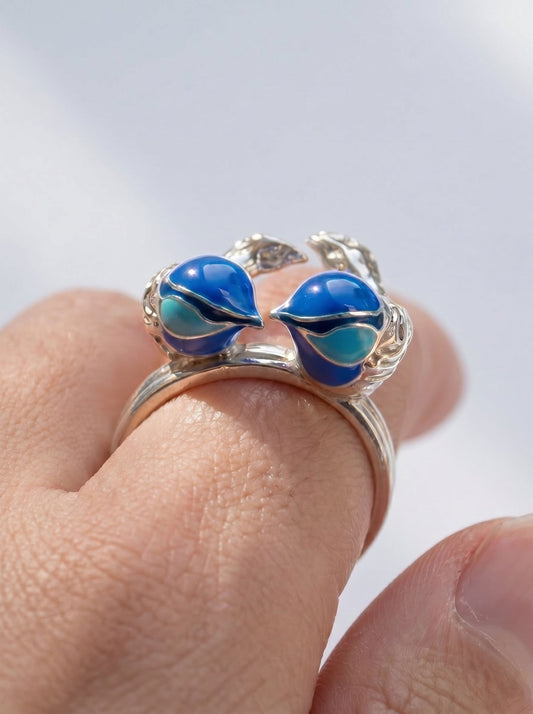 Close‑up of Fairy Wren stacking rings in sterling silver with hand‑applied blue enamel, showing the two birds facing each other in a heart‑like form.