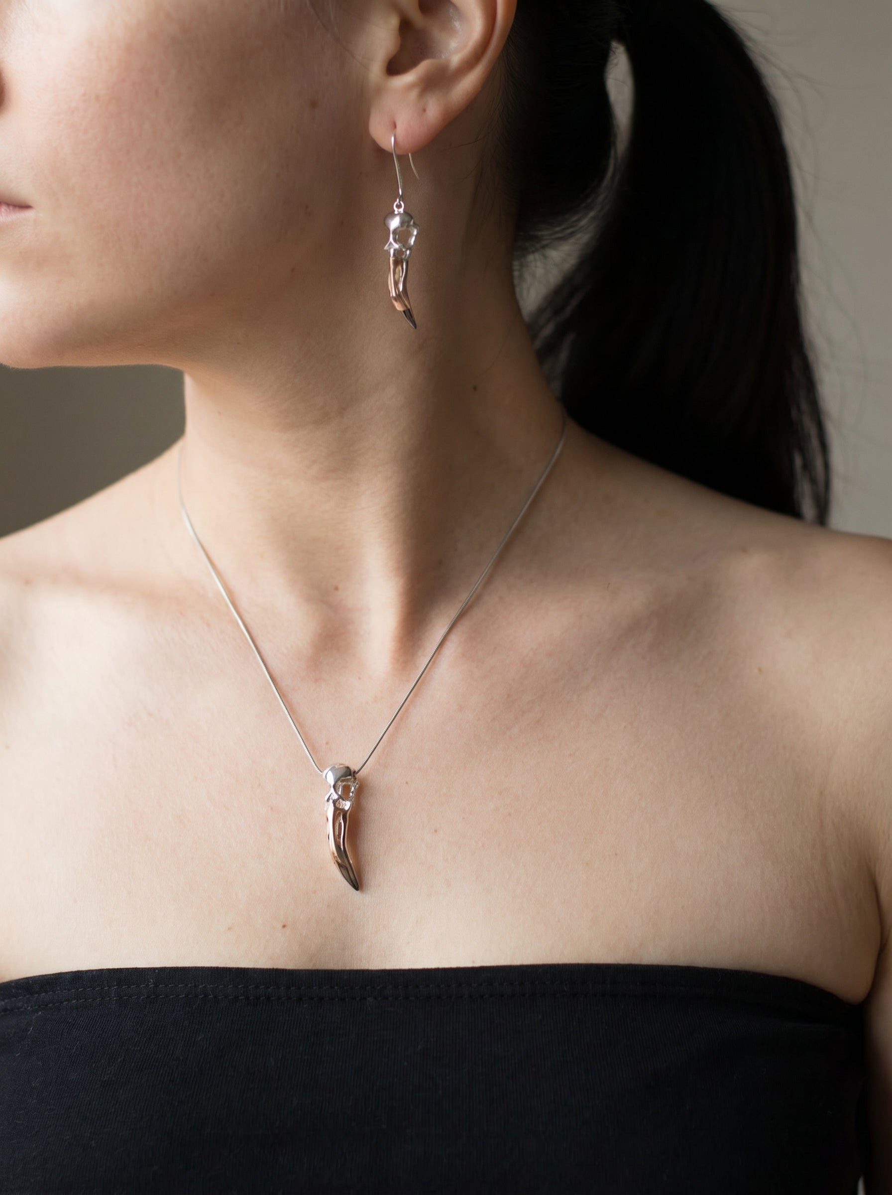 Flamingo Skull Drop Earrings worn with matching pendant, showing elongated silhouette and mixed‑metal tones against natural light.