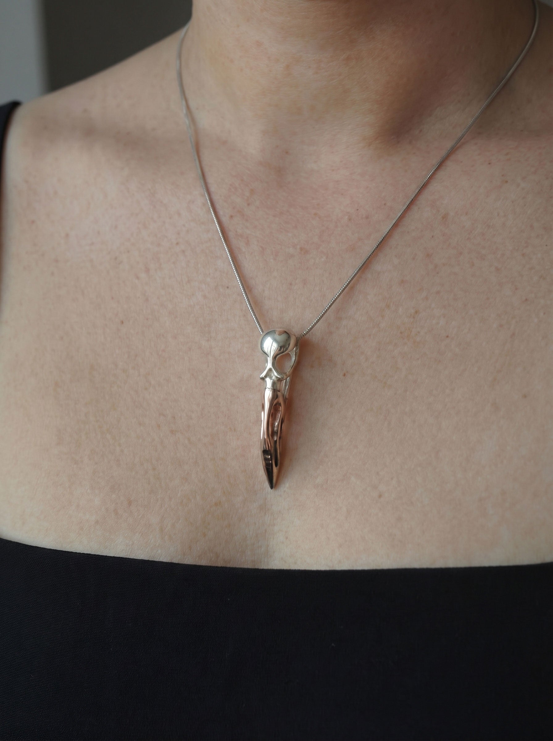 Flamingo Skull Pendant worn against black top, showing refined silhouette and interplay of silver, rhodium, and rose‑gold tones.