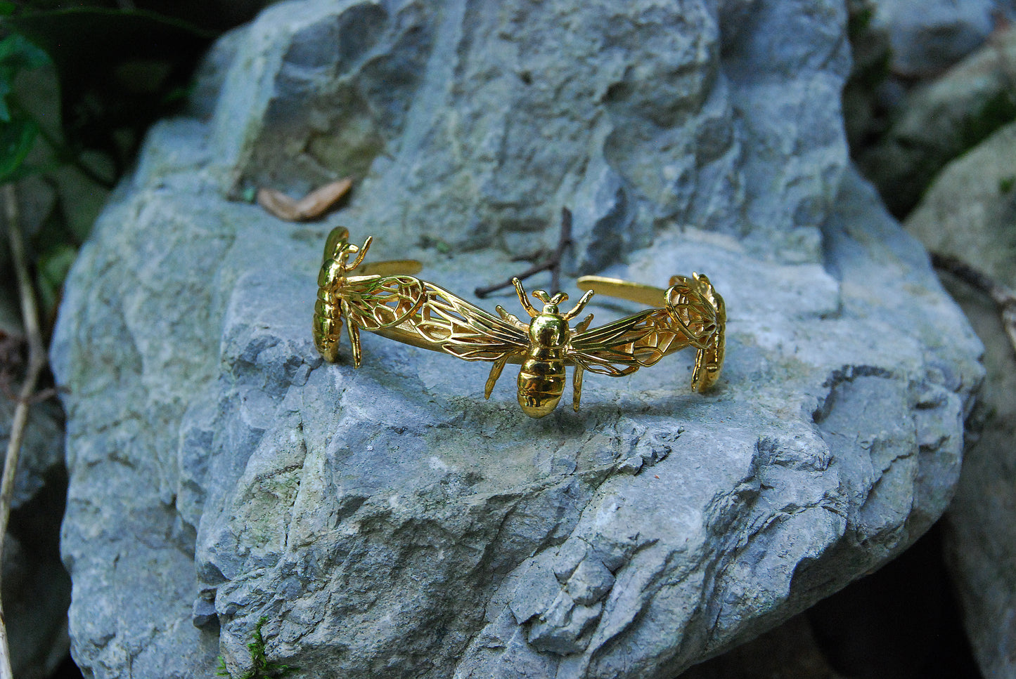 Nature-inspired bee bracelet in gold resting on moss for organic, earthy feel.