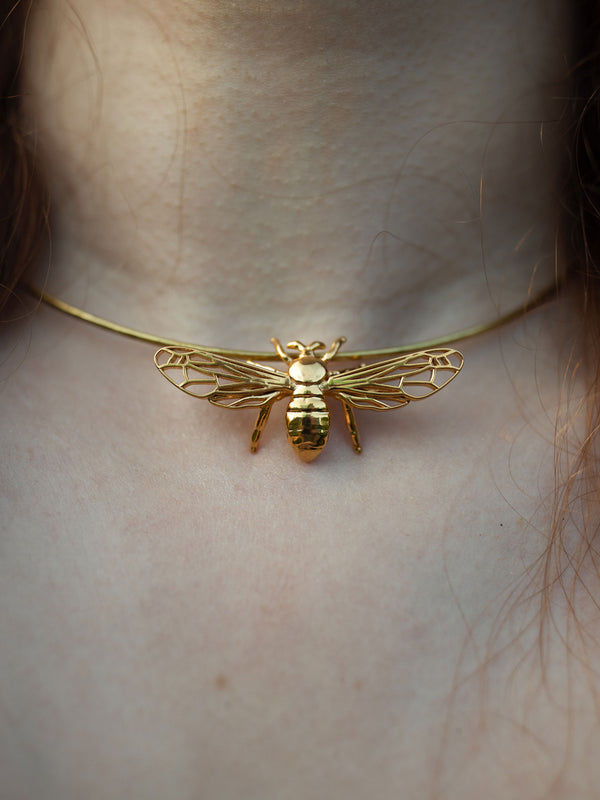 Close-up of model wearing silver and gold bee pendant necklace highlighting intricate details
