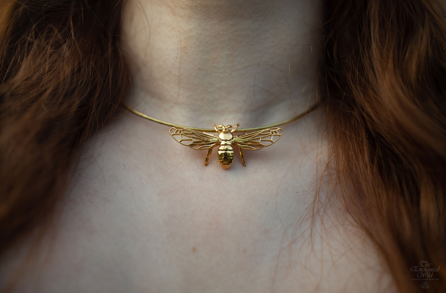 Close-up of model wearing silver and gold bee pendant necklace highlighting intricate details