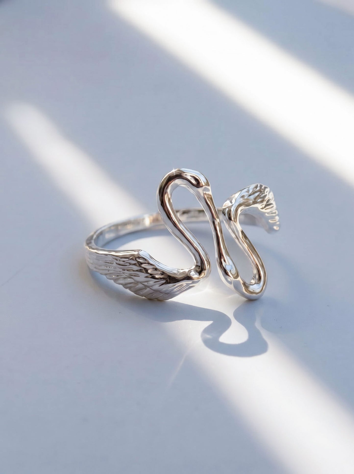 Close-up of Heron Kiss Ring in sterling silver, showing two mirrored herons meeting in an open silhouette with polished sculptural detail.