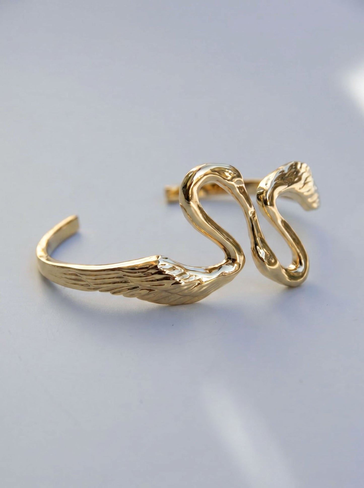 Heron Kiss Bracelet Cuff in gold finish, displayed on neutral background, capturing elegant curvature and reflective detail.
