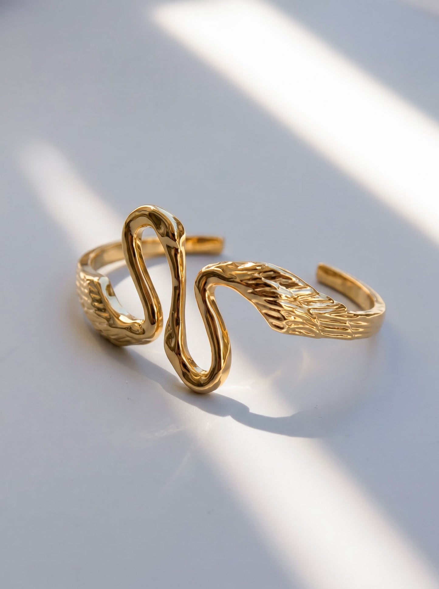 Heron Kiss Bracelet Cuff photographed with soft shadows, emphasizing feathered texture and architectural movement.