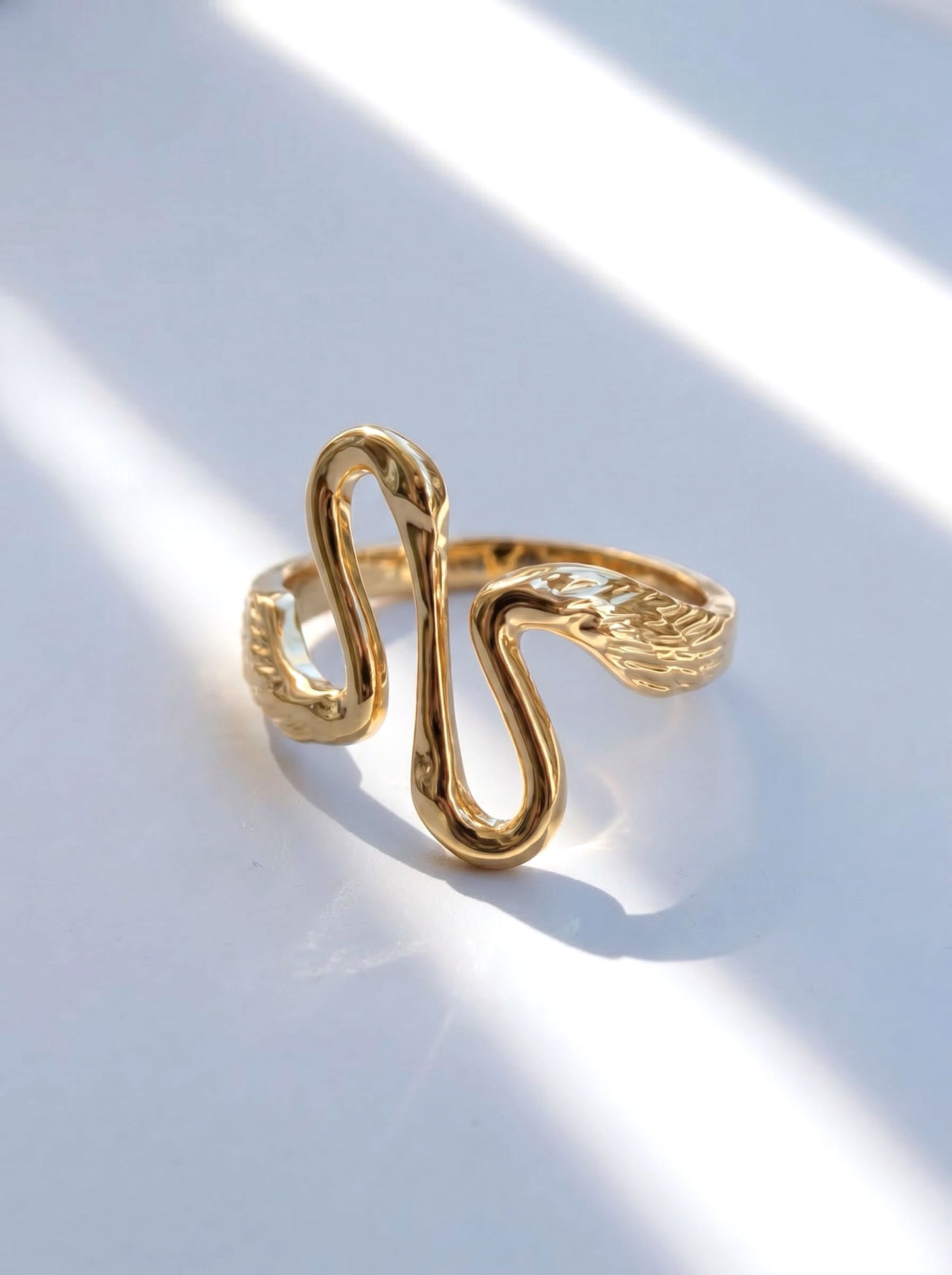 Angled view of Heron Kiss Ring in gold, showing the upward and downward heron forms curving toward each other.