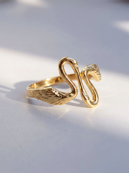 Heron Kiss Ring in gold finish, photographed in sunlight, showing two sculpted herons meeting in mirrored symmetry.