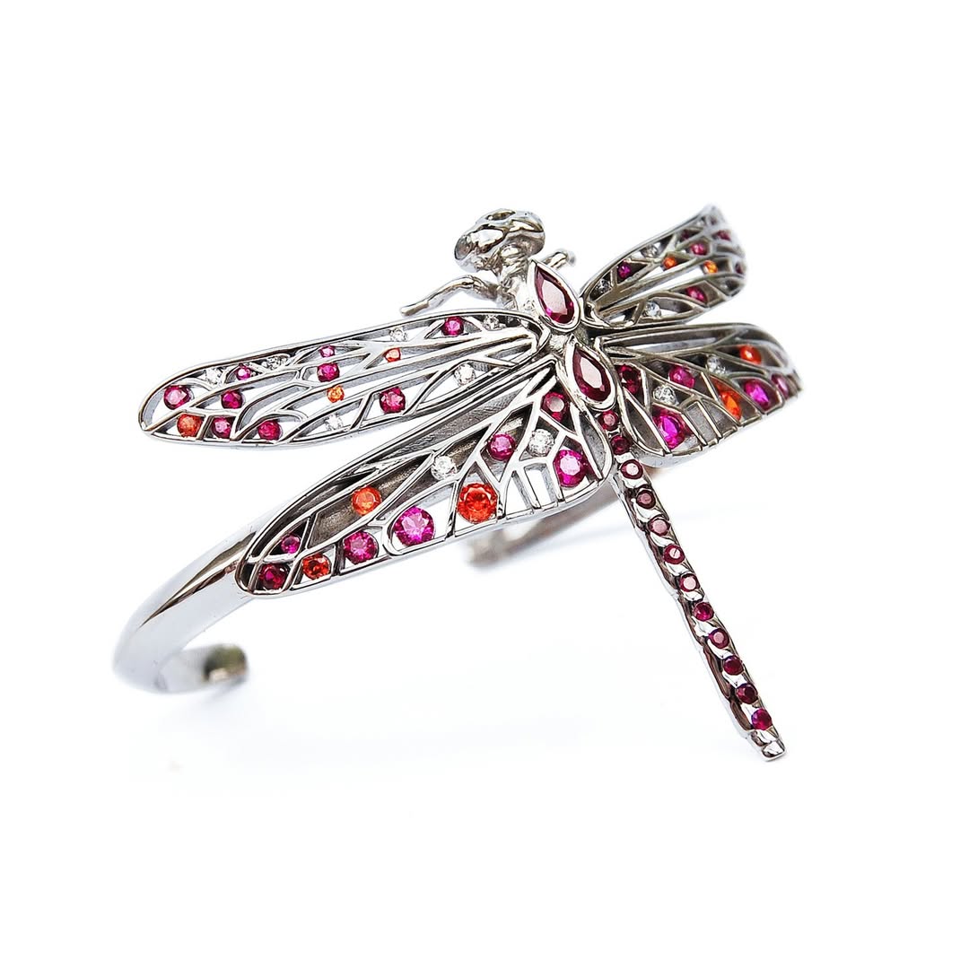 Horizontal display of sterling silver dragonfly jewelry with red, pink, orange, and white zirconia stones on white background