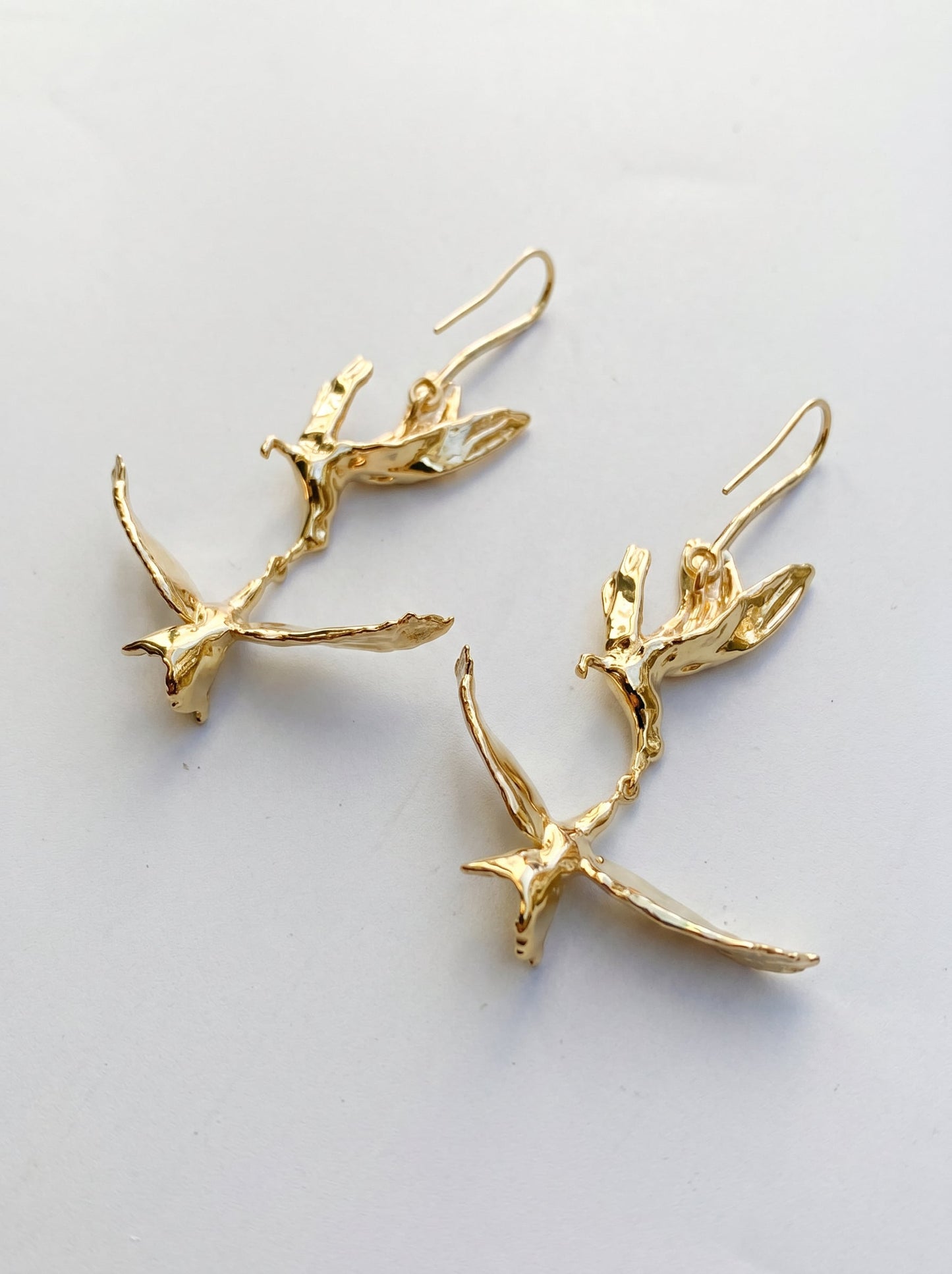 Kiss in Flight Arctic Tern Earrings photographed flat on white surface, capturing clean lines and sculptural symmetry.