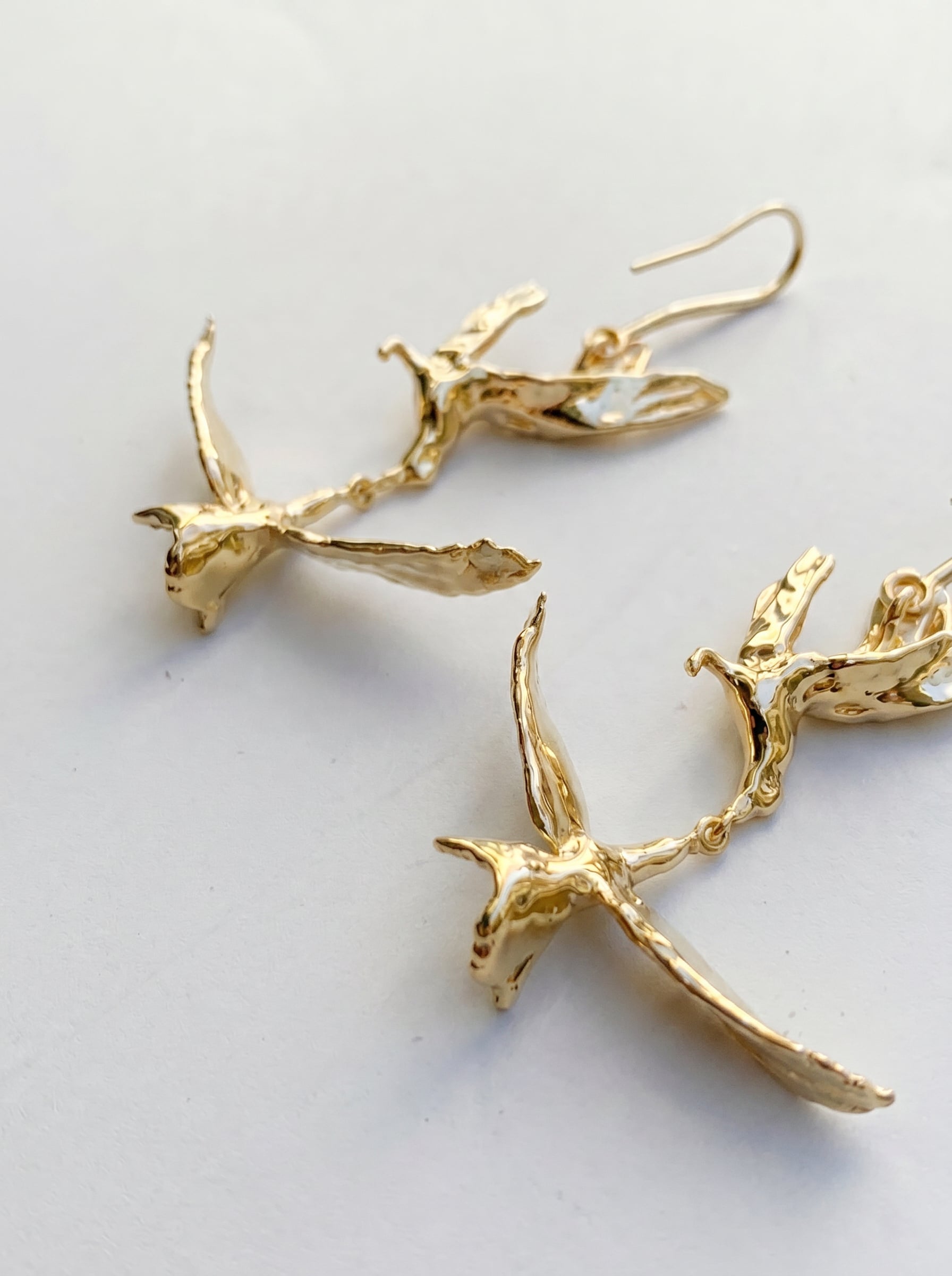 Angled view of Kiss in Flight Arctic Tern Earrings in gold, emphasizing fluid motion and refined Art Nouveau balance.