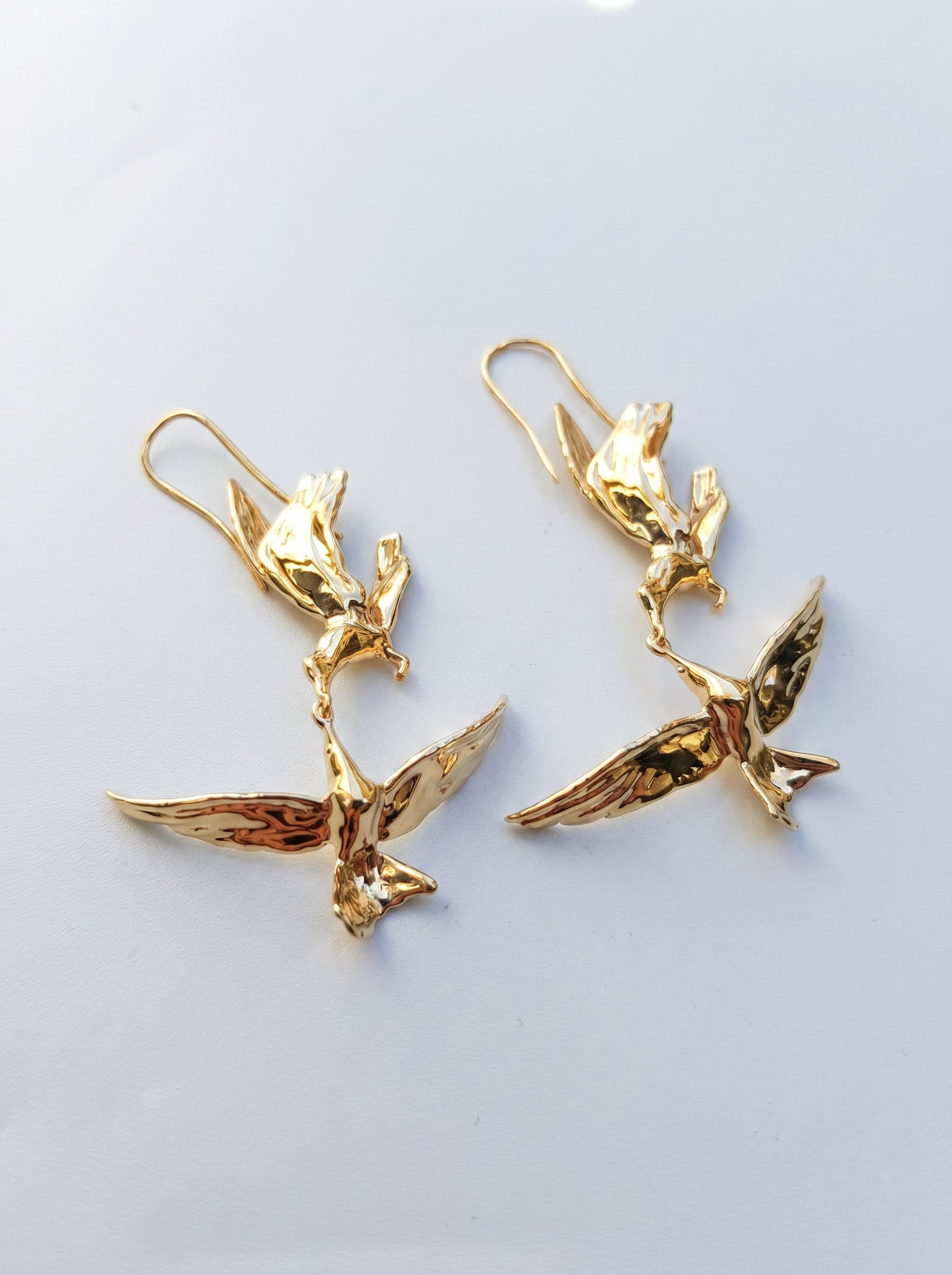 Kiss in Flight Arctic Tern Earrings in gold finish photographed as a pair, showing sculptural balance and reflective surfaces.