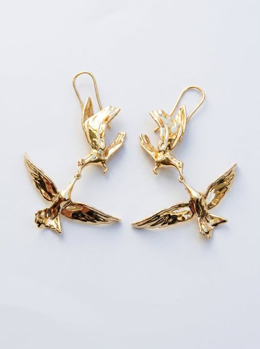 Kiss in Flight Arctic Tern Earrings in gold finish, photographed in sunlight, showing two sculpted birds meeting mid‑air in mirrored symmetry.