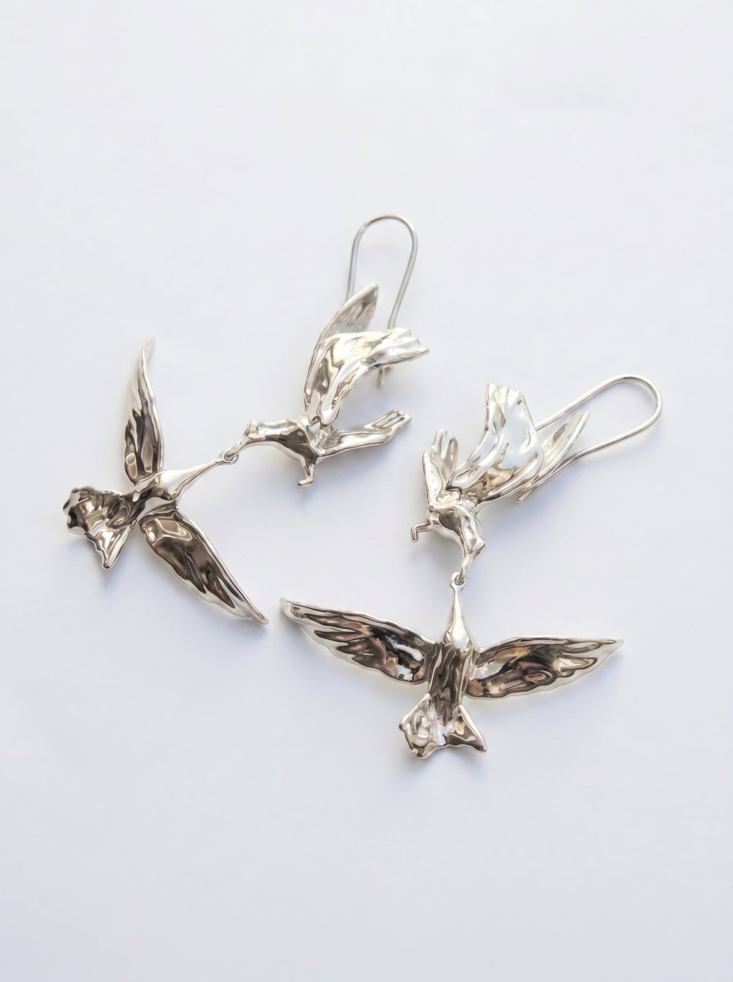 Kiss in Flight Arctic Tern Earrings in silver finish photographed flat, showing mirrored bird forms and crisp sculptural detail.