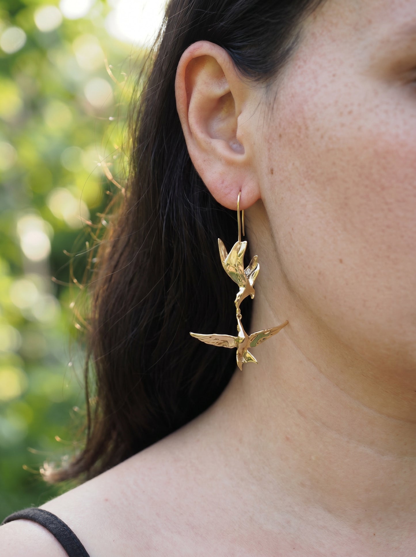 Kiss in Flight Arctic Tern Earrings worn on ear, highlighting sculptural silhouettes and soft gold reflections.