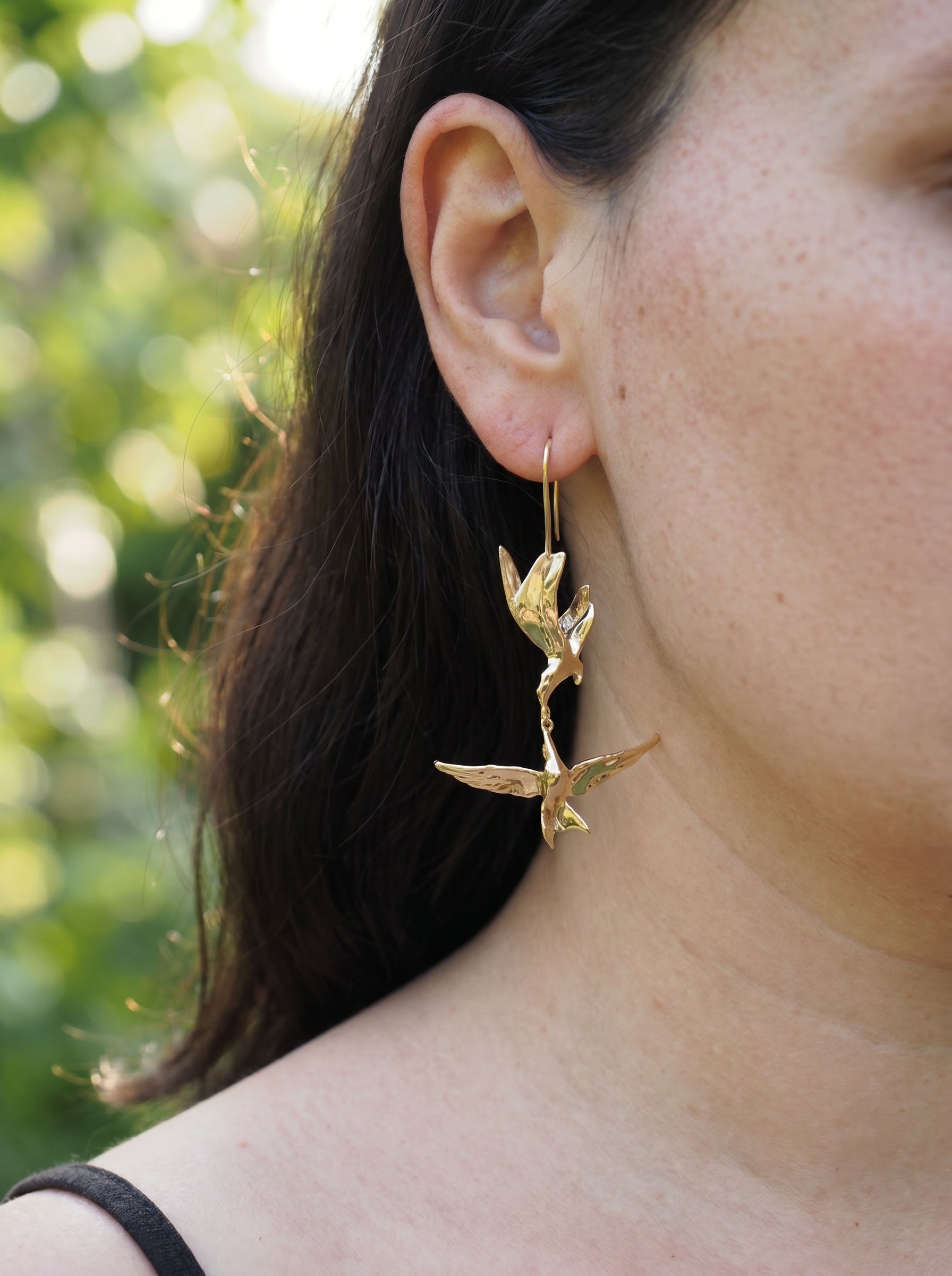 Kiss in Flight Arctic Tern Earrings worn on ear, highlighting sculptural silhouettes and soft gold reflections.