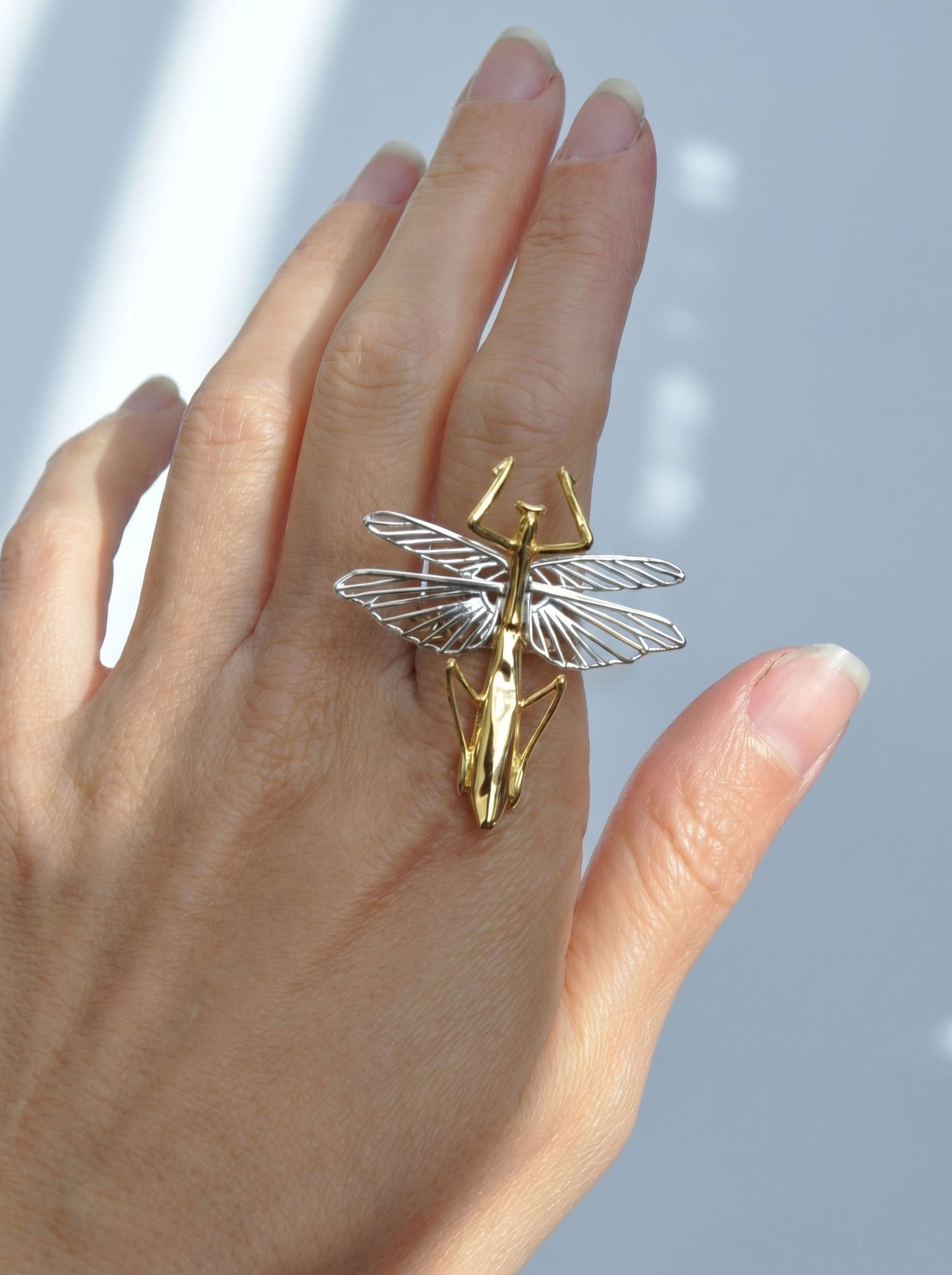 Praying mantis ring with sterling‑silver wings and a 14k gold‑plated body shown on the hand.