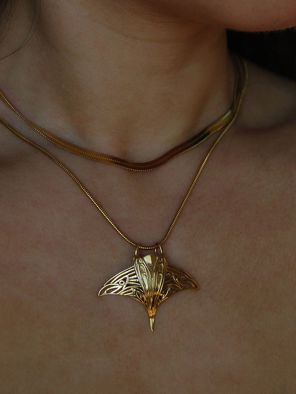 Model wearing gold manta ray pendant necklace, showcasing ocean-inspired jewelry.