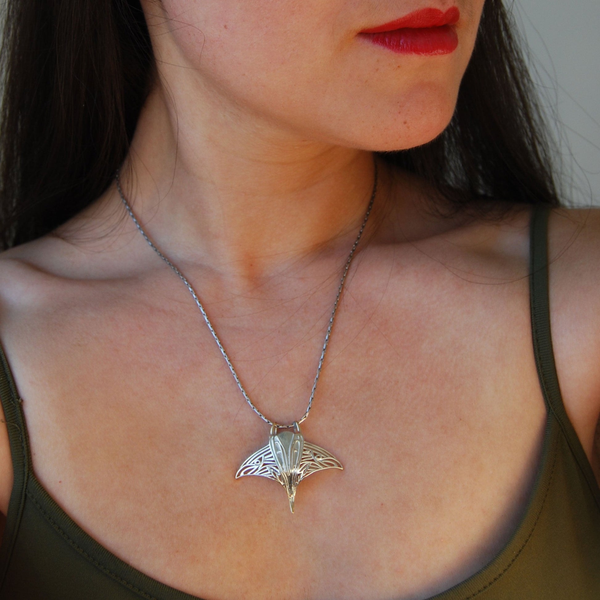 Model wearing sterling silver manta ray pendant, highlighting marine life jewelry design.