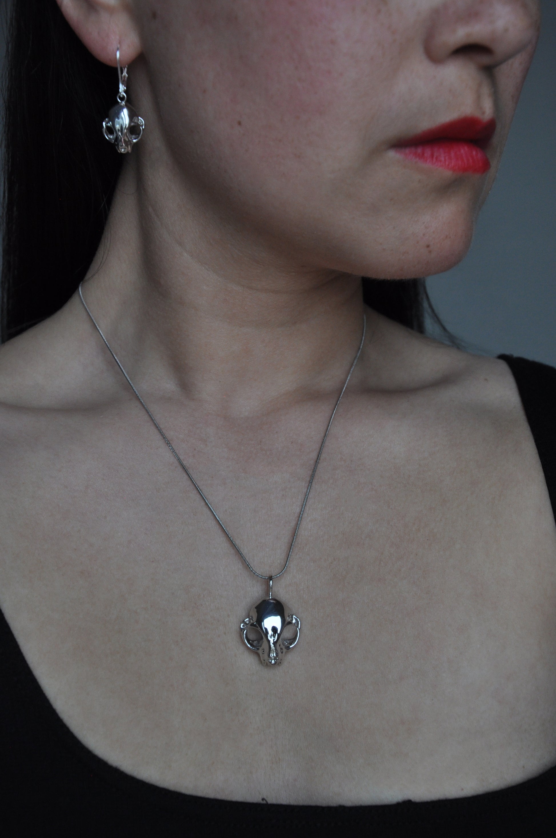 Model wearing silver feline skull drop earrings and matching pendant, showcasing the gothic jewelry set.