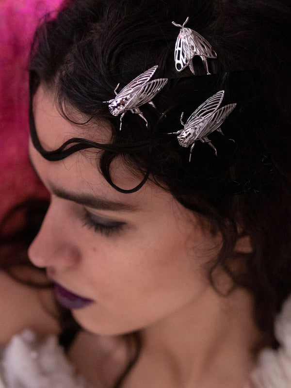 Model wearing silver Cicada hair pins and a Tiger Moth hair accessory, styled in a nature-inspired look that highlights handcrafted insect jewelry with metallic finishes.