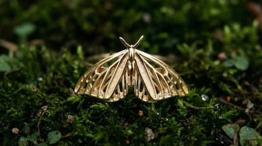 Gold butterfly-shaped pendant on a green moss background