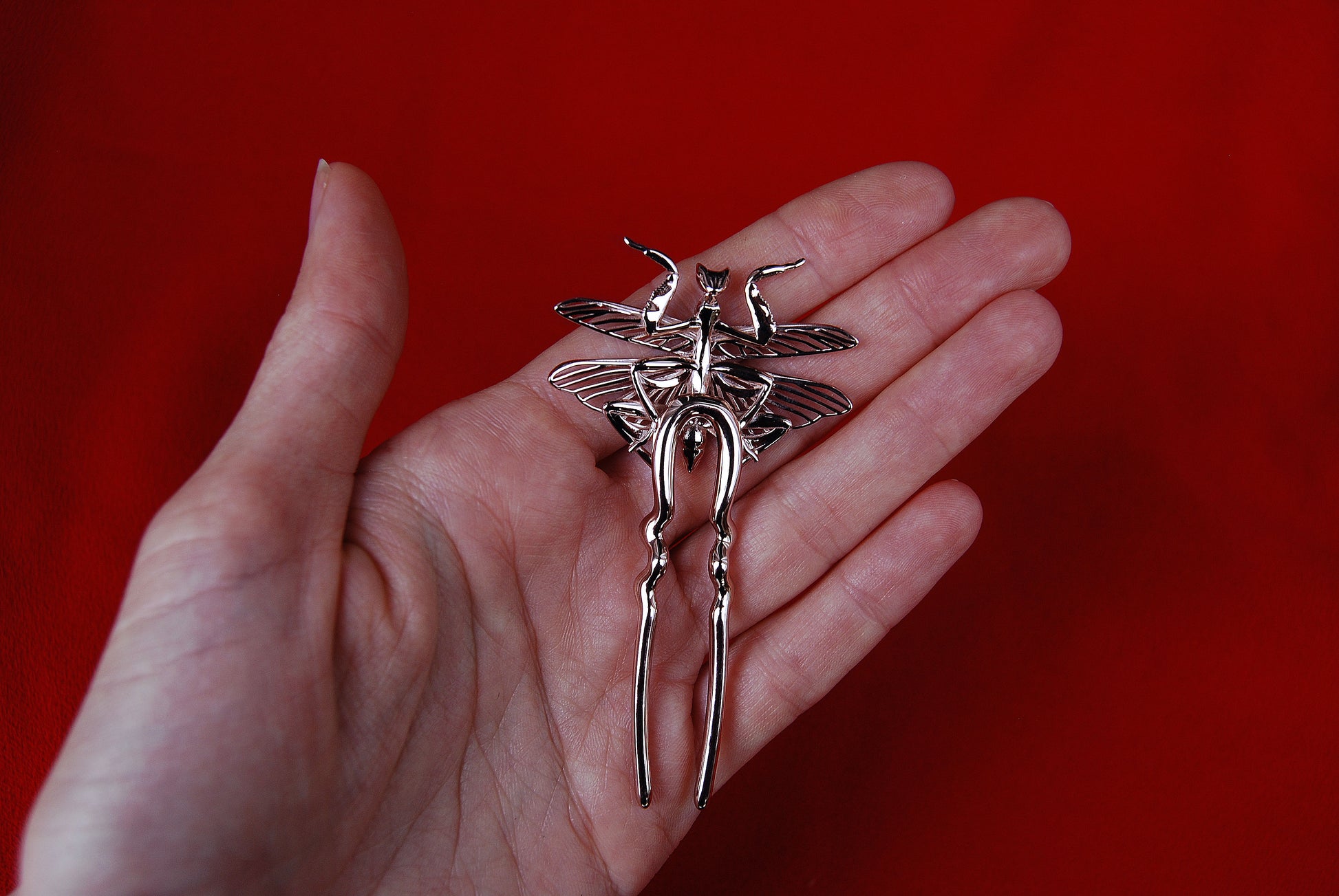 Single Orchid Mantis hairpin held delicately in hand, sculptural and surreal.